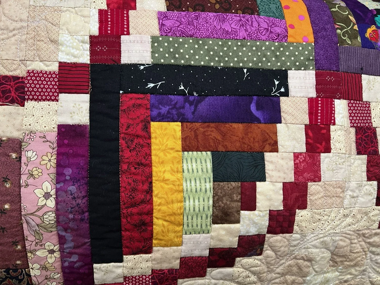Close-up of a colorful patchwork quilt made of various patterned fabric squares and rectangles.