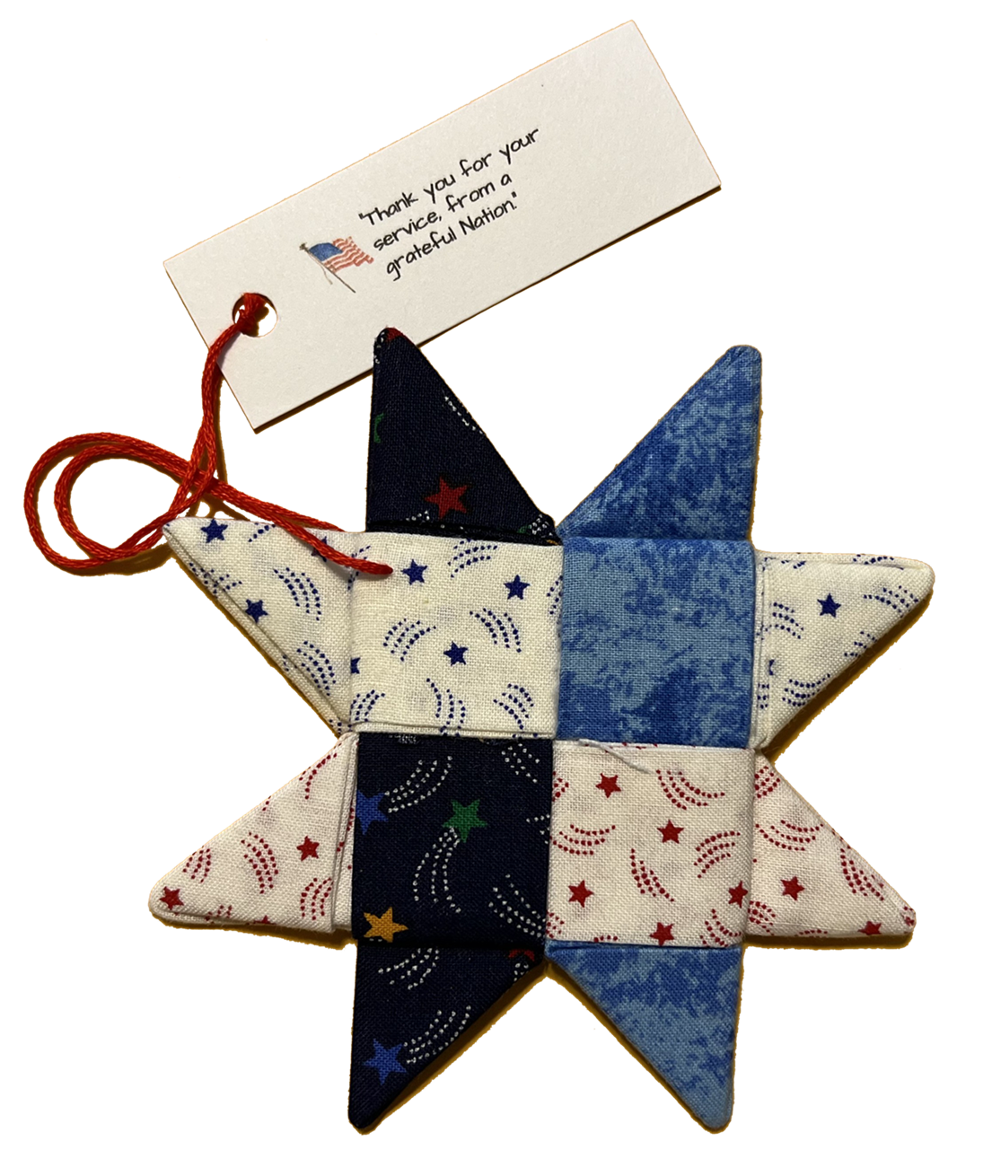 A patriotic quilted star ornament with a red string loop and a thank you tag. The ornament features red, white, and blue fabric patches with star and swirl patterns.