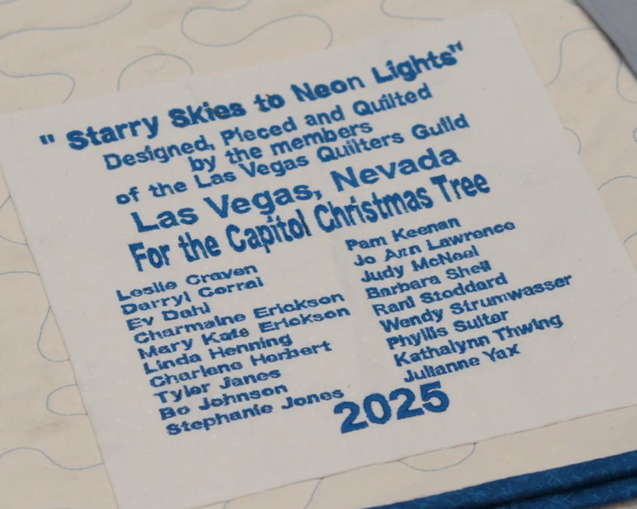 A commemorative quilt label sewn onto the back of the Las Vegas Quilters Guild “Starry Skies to Neon Lights” quilt identifying the project and contributors. 