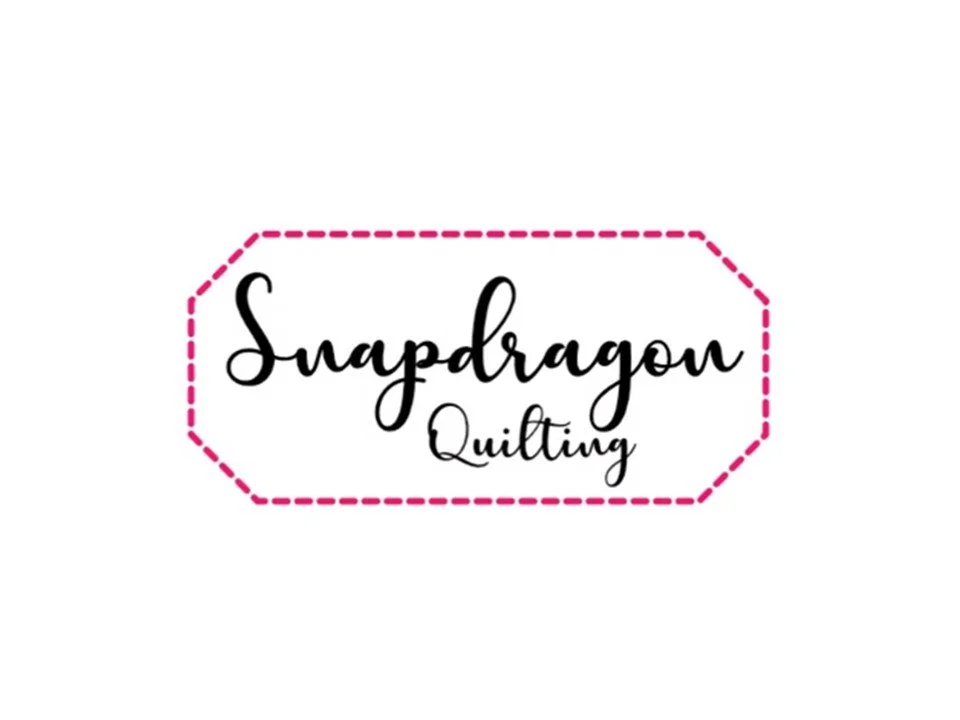 Logo reading "Snapdragon Quilting" with black cursive text inside a pink dashed border.