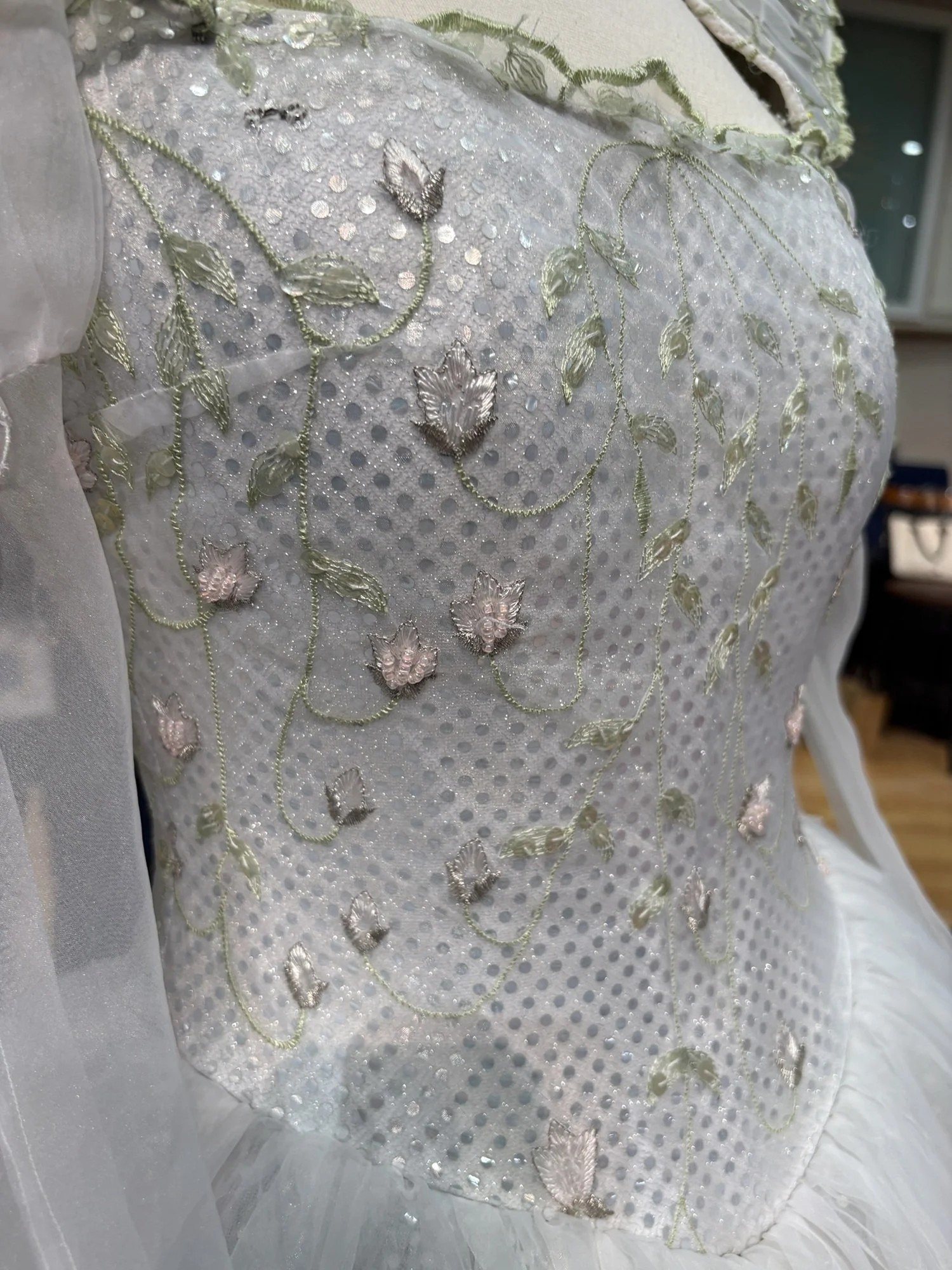 Close-up of the bodice showing delicate floral embroidery and shimmering details that create the gown’s magical, ethereal effect.