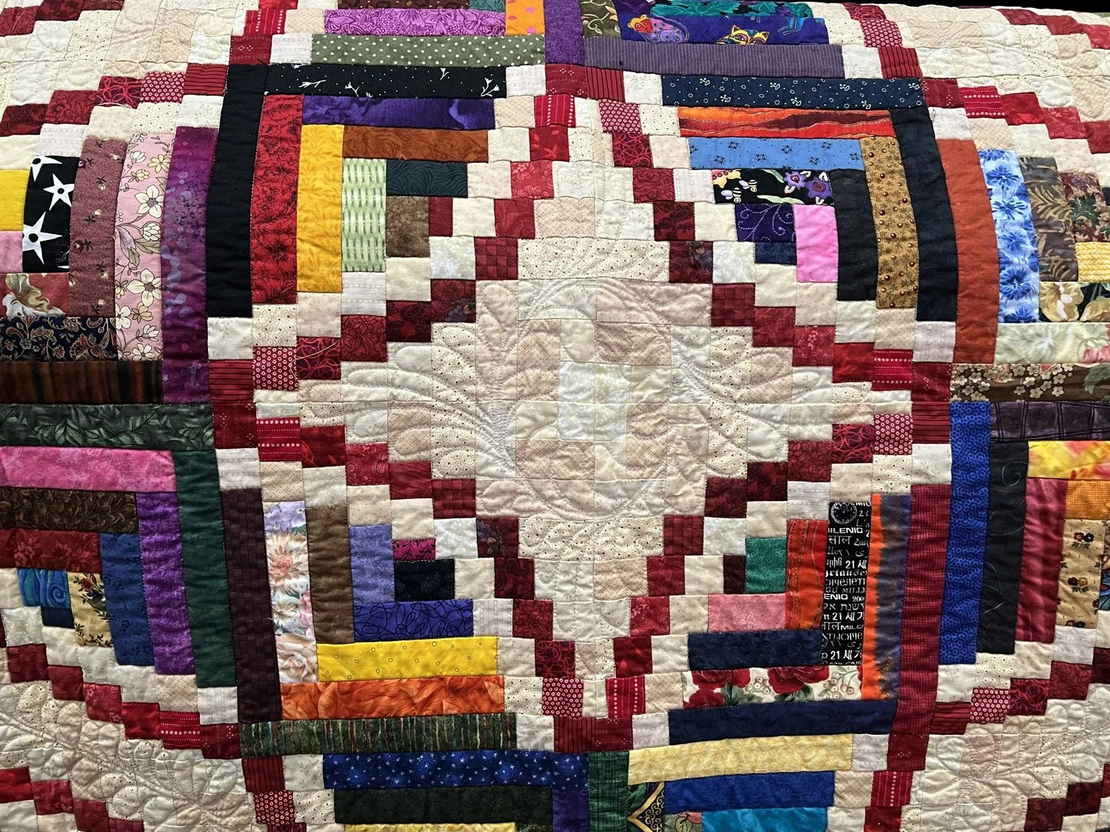 A colorful quilt with a patchwork of various fabric squares and borders in multiple colors and patterns.