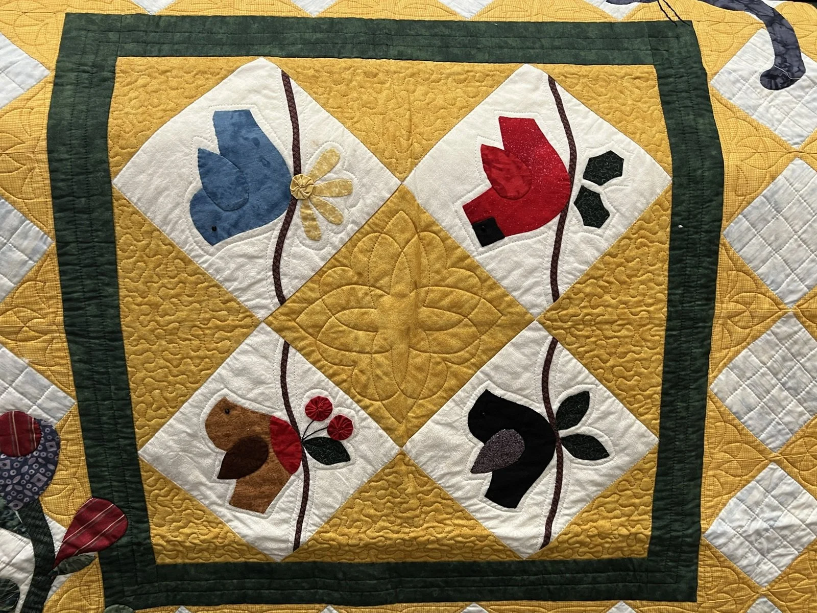 A quilt with a yellow background featuring four appliquéd animal designs.
