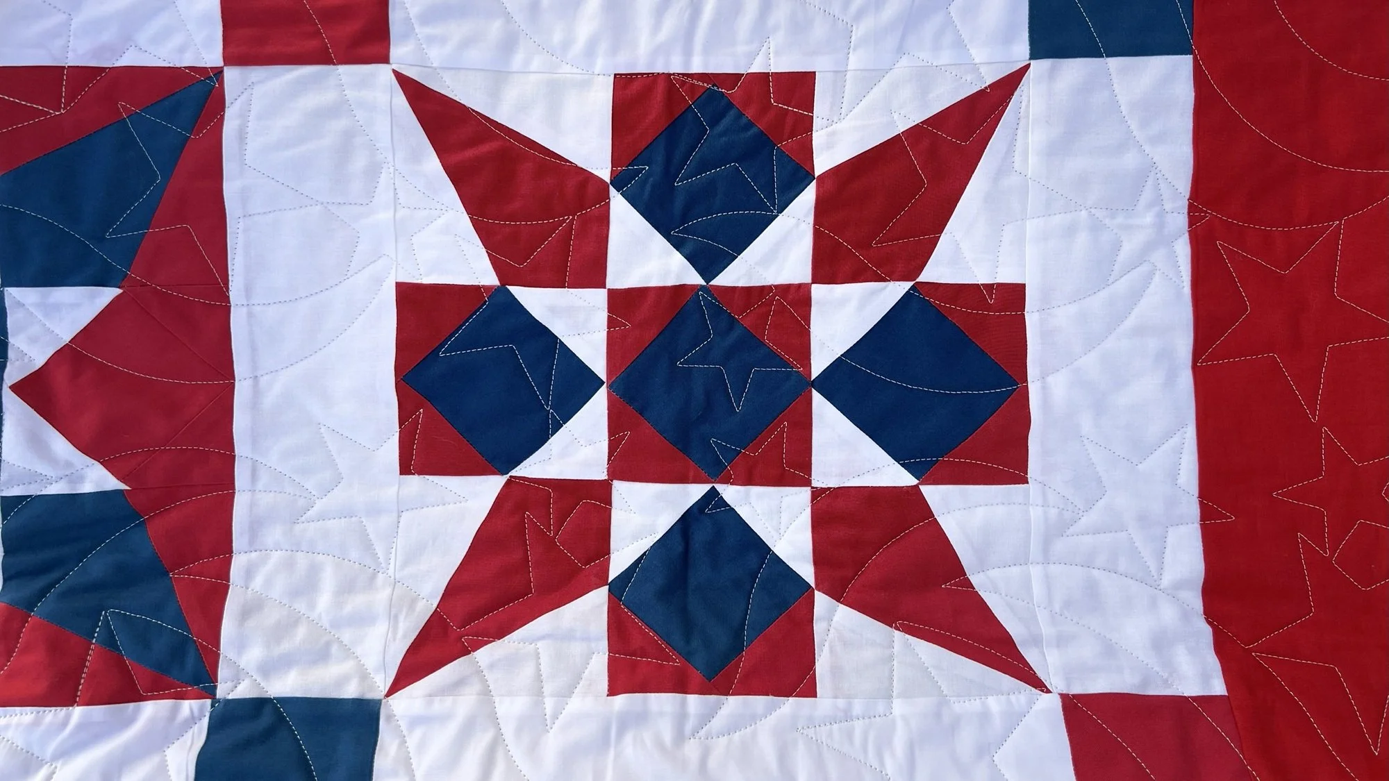 Close-up of a quilt with a patriotic star pattern in red, white, and blue fabrics.