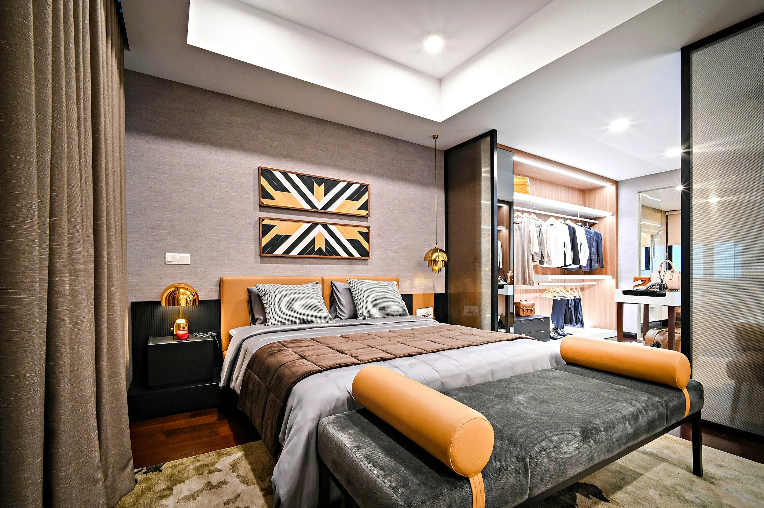 Modern bedroom with a bed, bedside tables, geometric artwork above the bed, and a walk-in closet with hanging clothes and shelves.