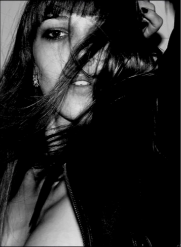 Schwarzweißfoto einer lachenden Frau mit dunklen Haaren, teilweise im Gesicht und vor dem Auge verschleiert.