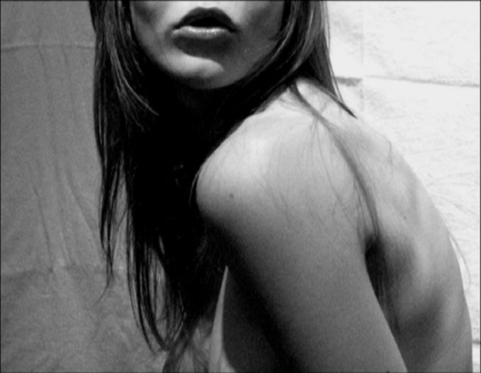 Schwarz-weiß-Fotografie eines Teils eines menschlichen Körpers, Fokus auf Schulter und Gesicht einer Frau.