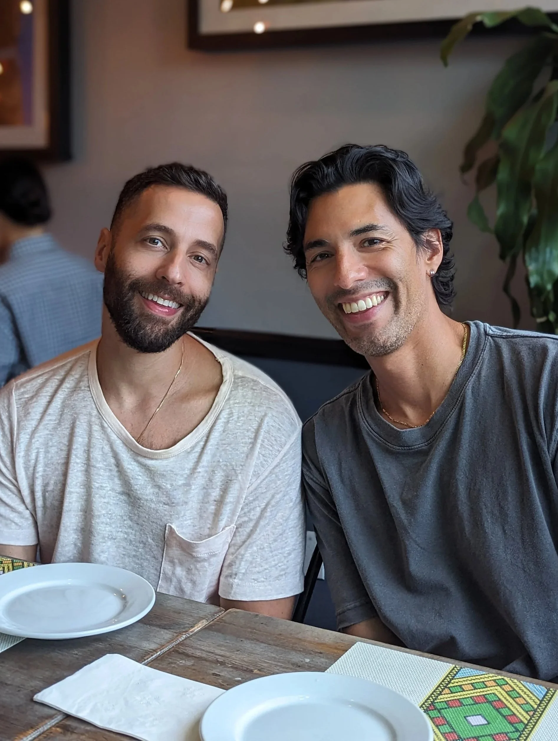 Two smiling men sitting at a restaurant table, posing for a photo.