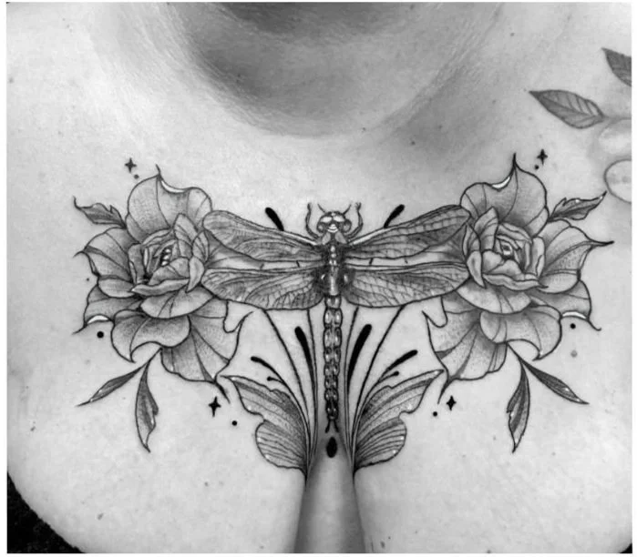 Tattoo of a dragonfly, blooming roses, and a butterfly on the chest.