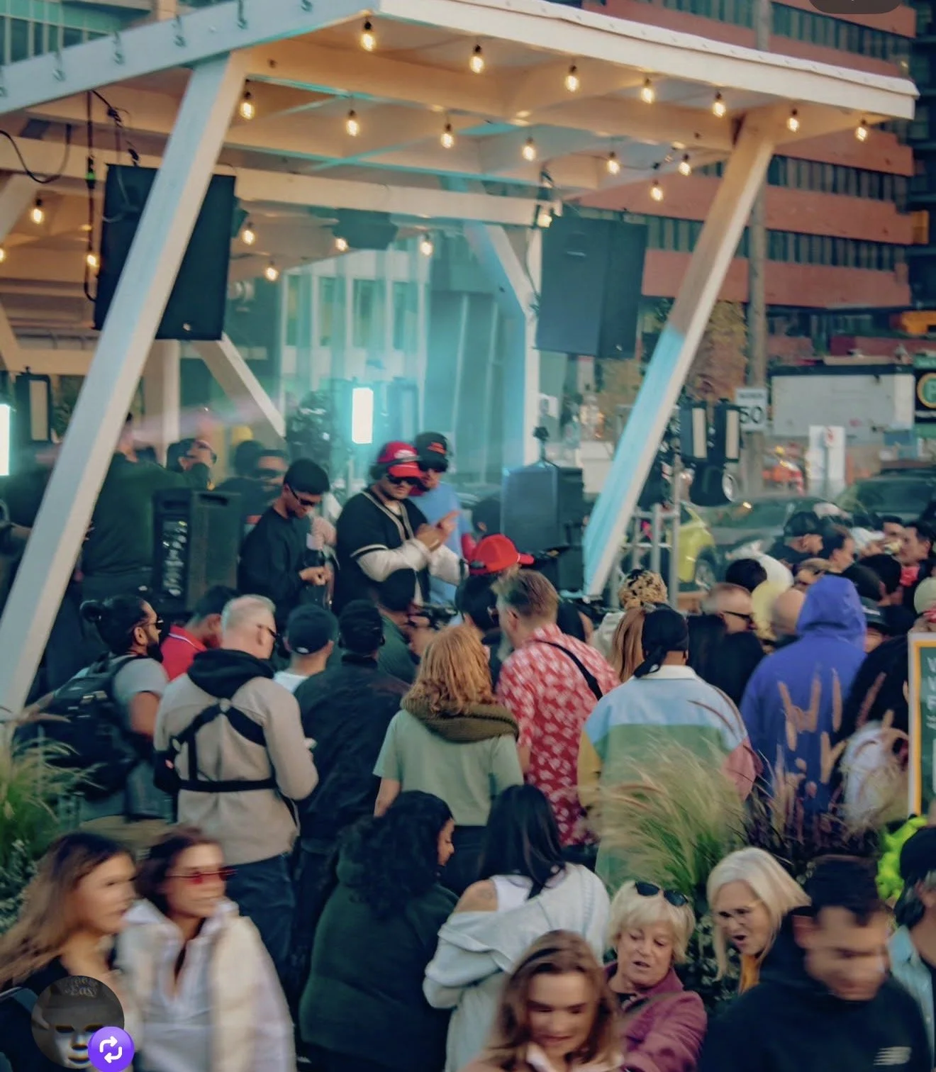 Crowd dancing at a Dos Leches DJ set with stage and string lights at an outdoor Calgary venue
