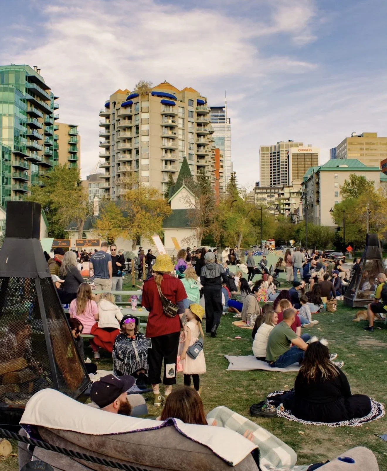 Dos Leches event crowd in a Calgary park with the city skyline in the background