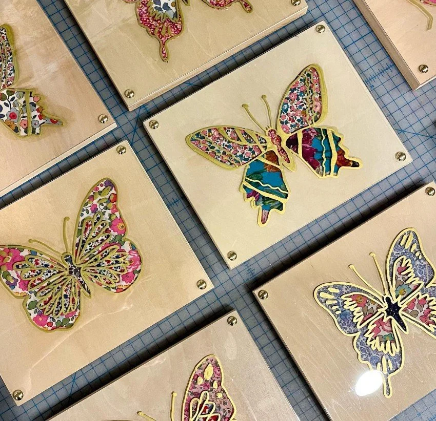 Multiple decorative butterfly wall art pieces with colorful patterns, mounted on wooden boards with metal screws.