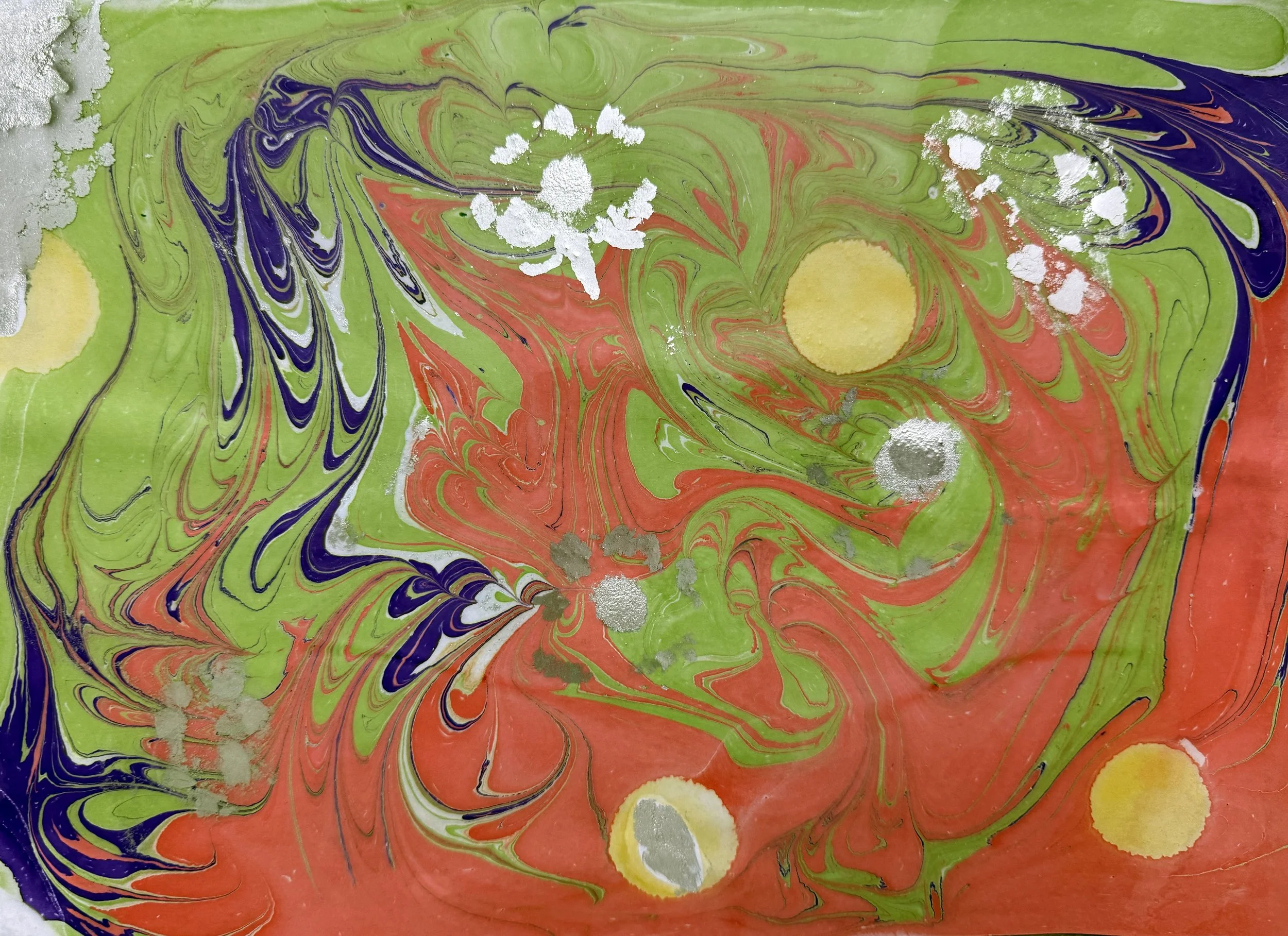 A colorful abstract pattern with swirling green, red, purple, and yellow hues, featuring splashes of white and silver paint.