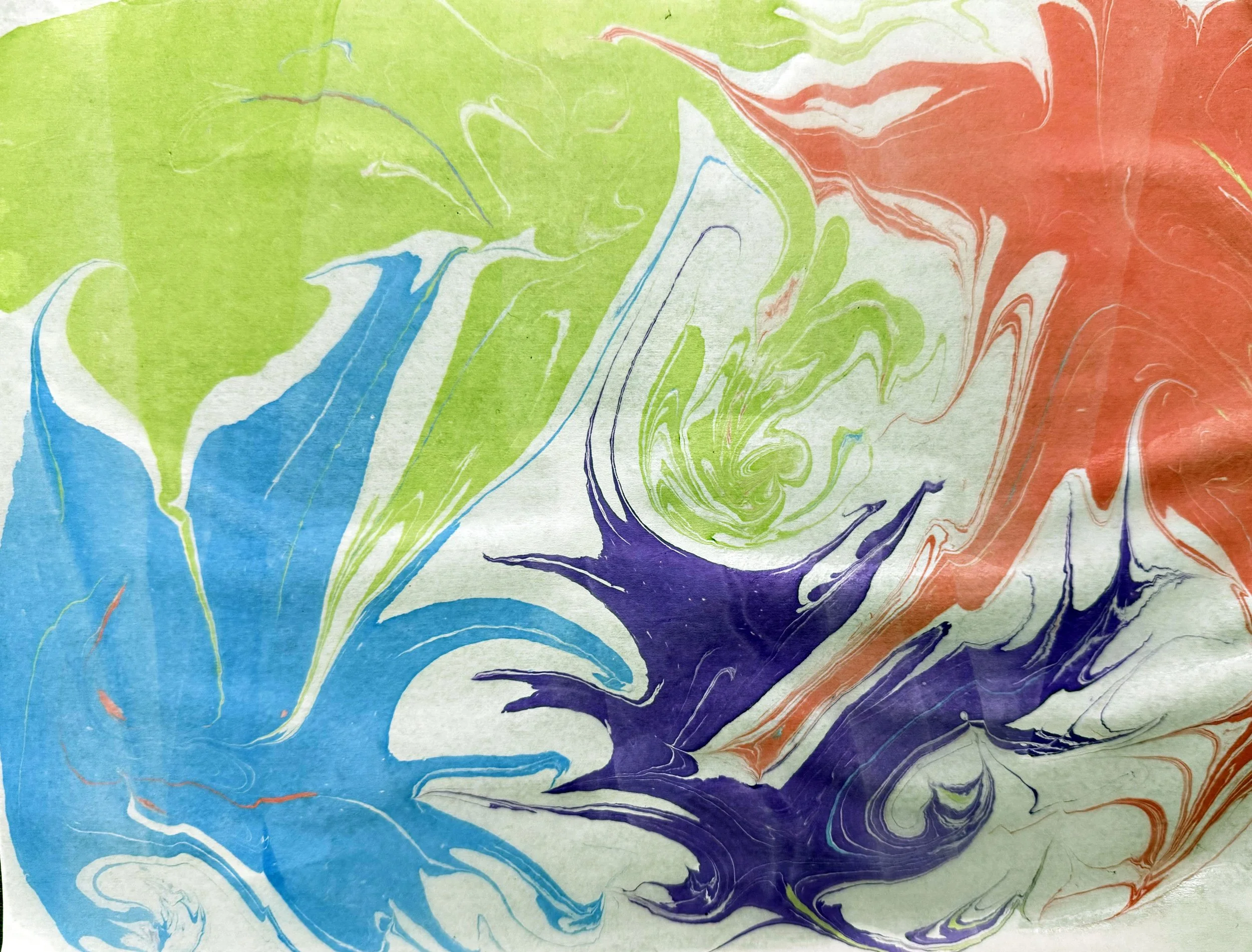 Colorful abstract marbled paper with swirls of green, blue, purple, and red on a textured surface.