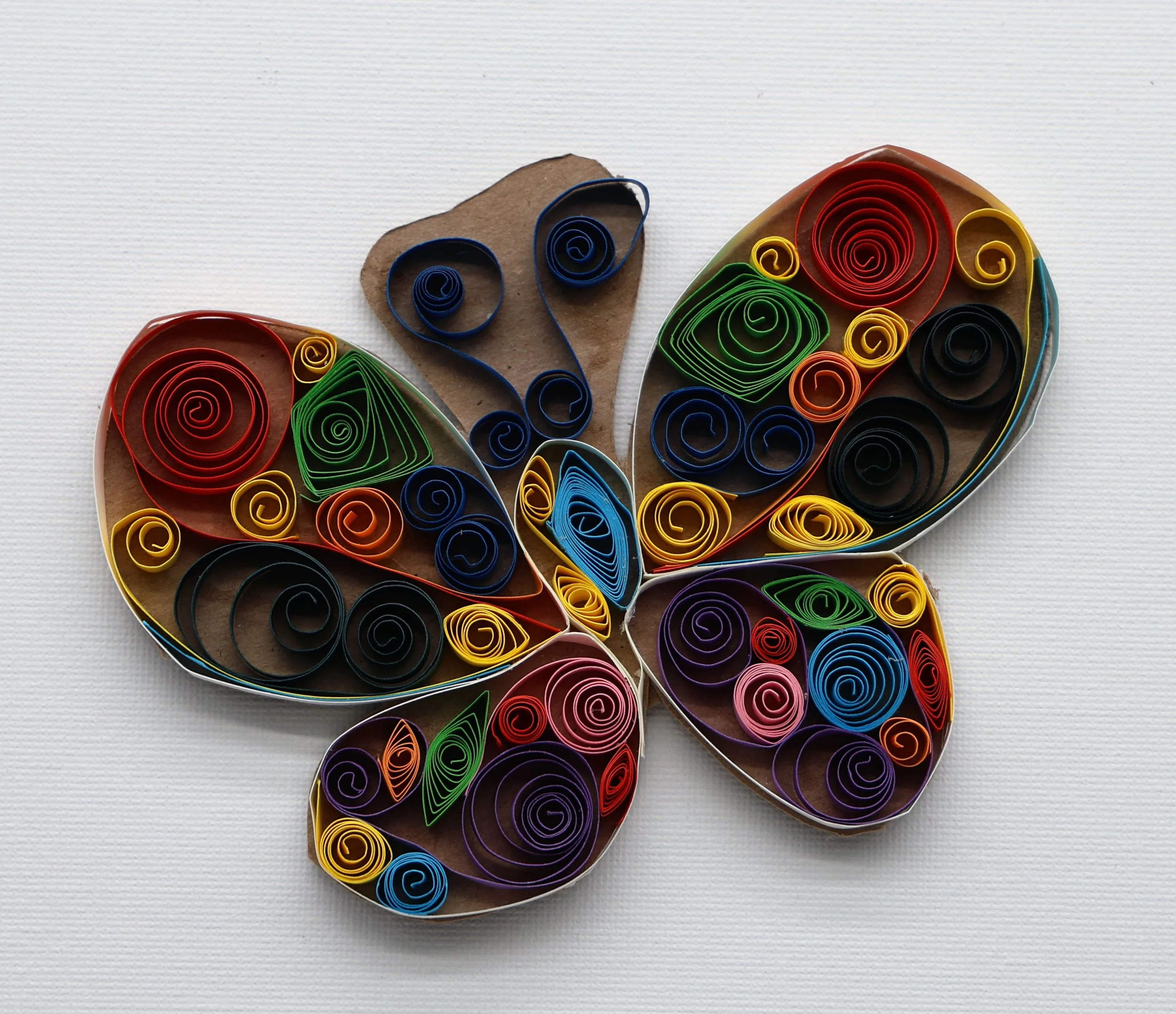 Colorful paper quilling art in the shape of a butterfly on a white background.