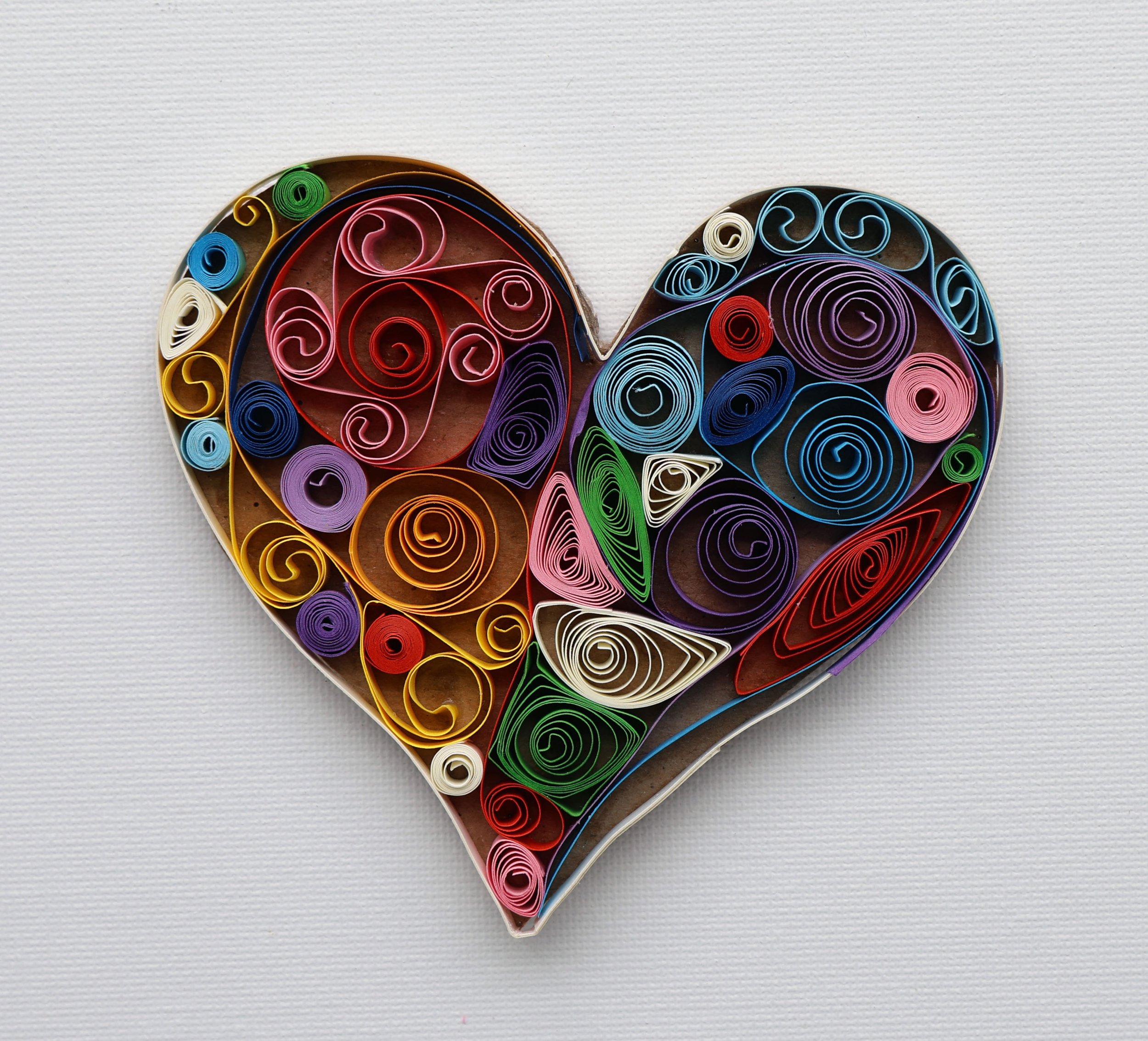 Colorful quilled paper art heart shape on white background.