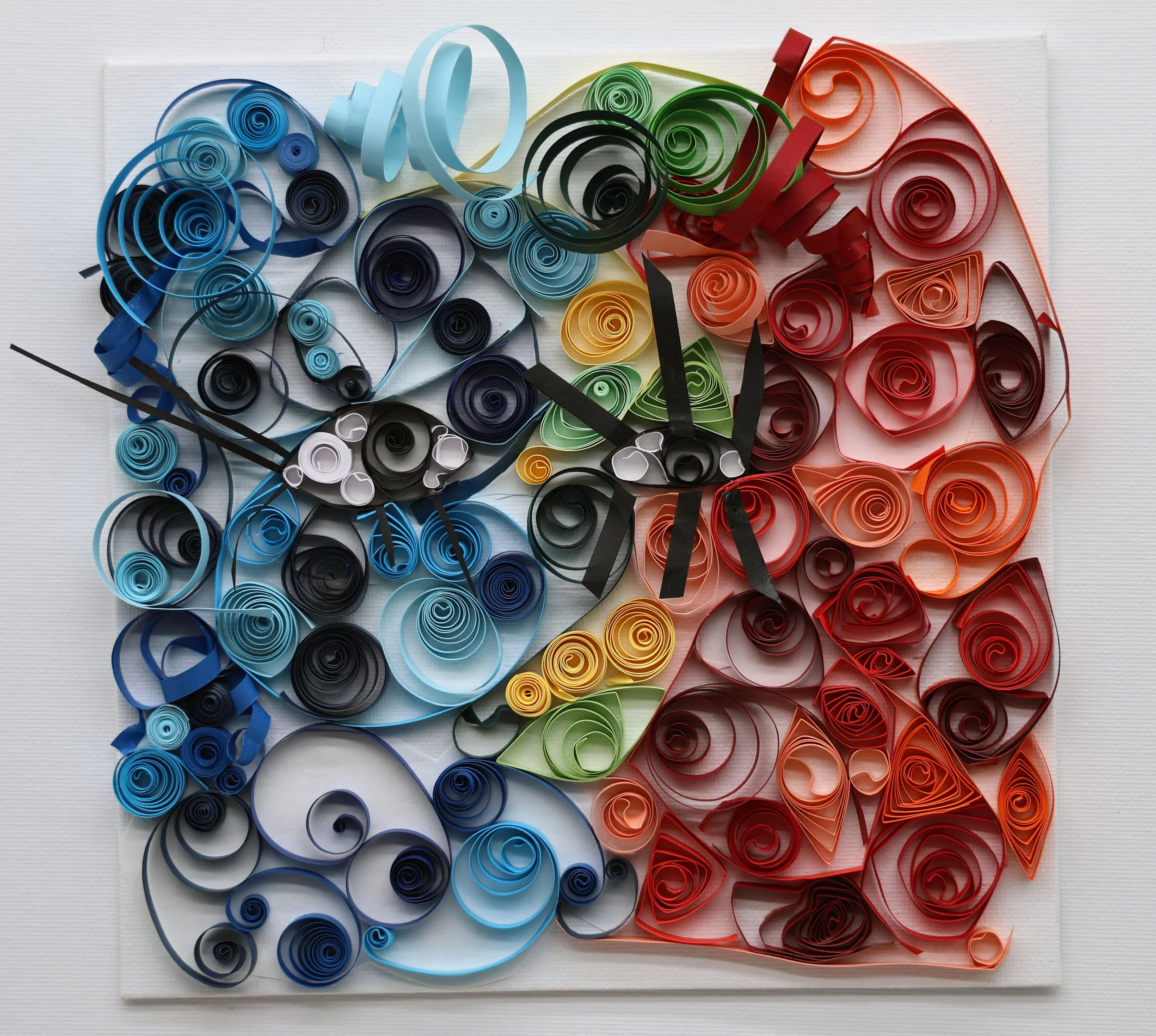 A colorful 3D paper quilled clock depicting the United States flag with red, white, blue, and green sections, clock hands in the center, and numerous spiral paper designs.