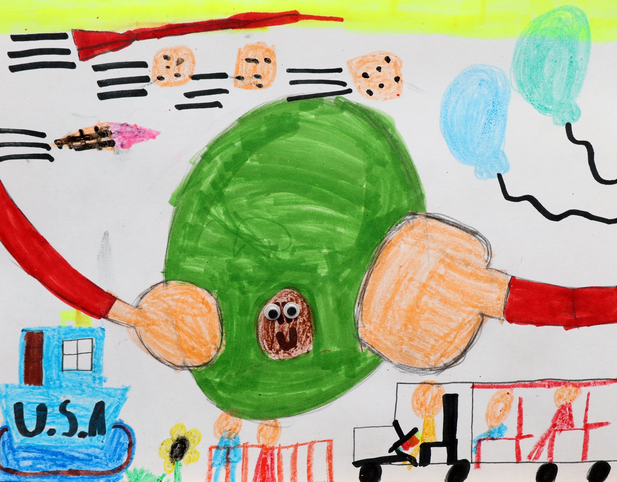 A child's drawing of a smiling green turtle with googly eyes, surrounded by flying airplanes, a house labeled 'U.S.A.', clouds, and other colorful shapes.