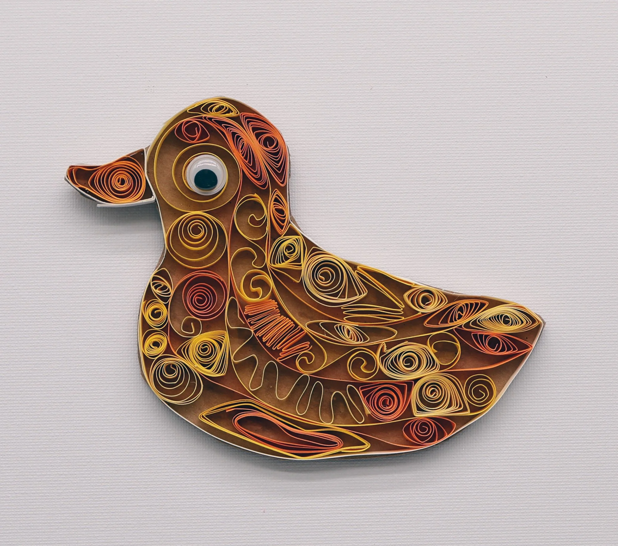 Decorative bird-shaped wall art made of colorful paper quilling against a plain white background.