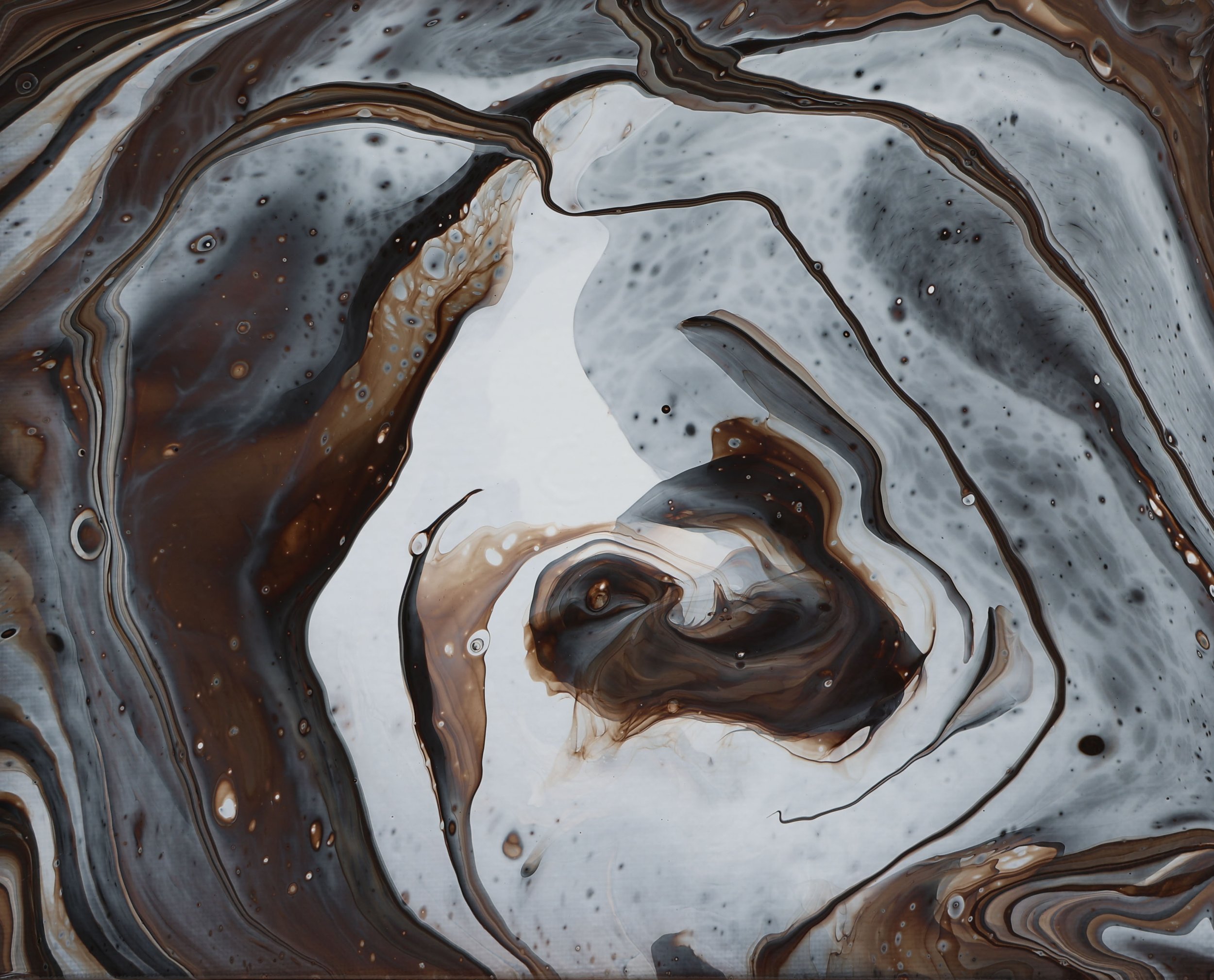 Swirling abstract pattern with black, brown, gray, and white colors, resembling fluid or ink in water.