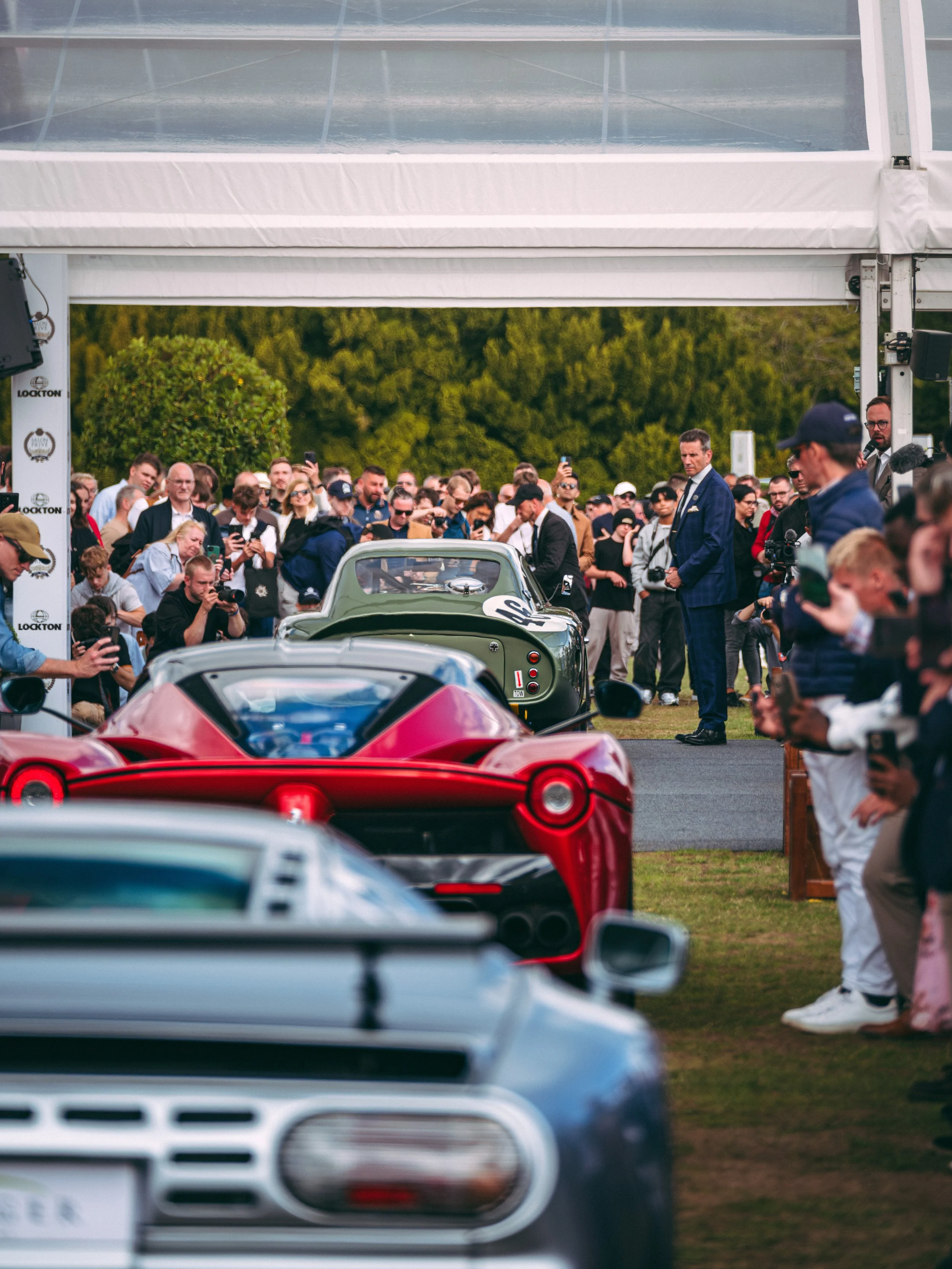 Bugatti EB110 SS, LaFerrari and Ason Martin DB4 surrounded by a Crowd