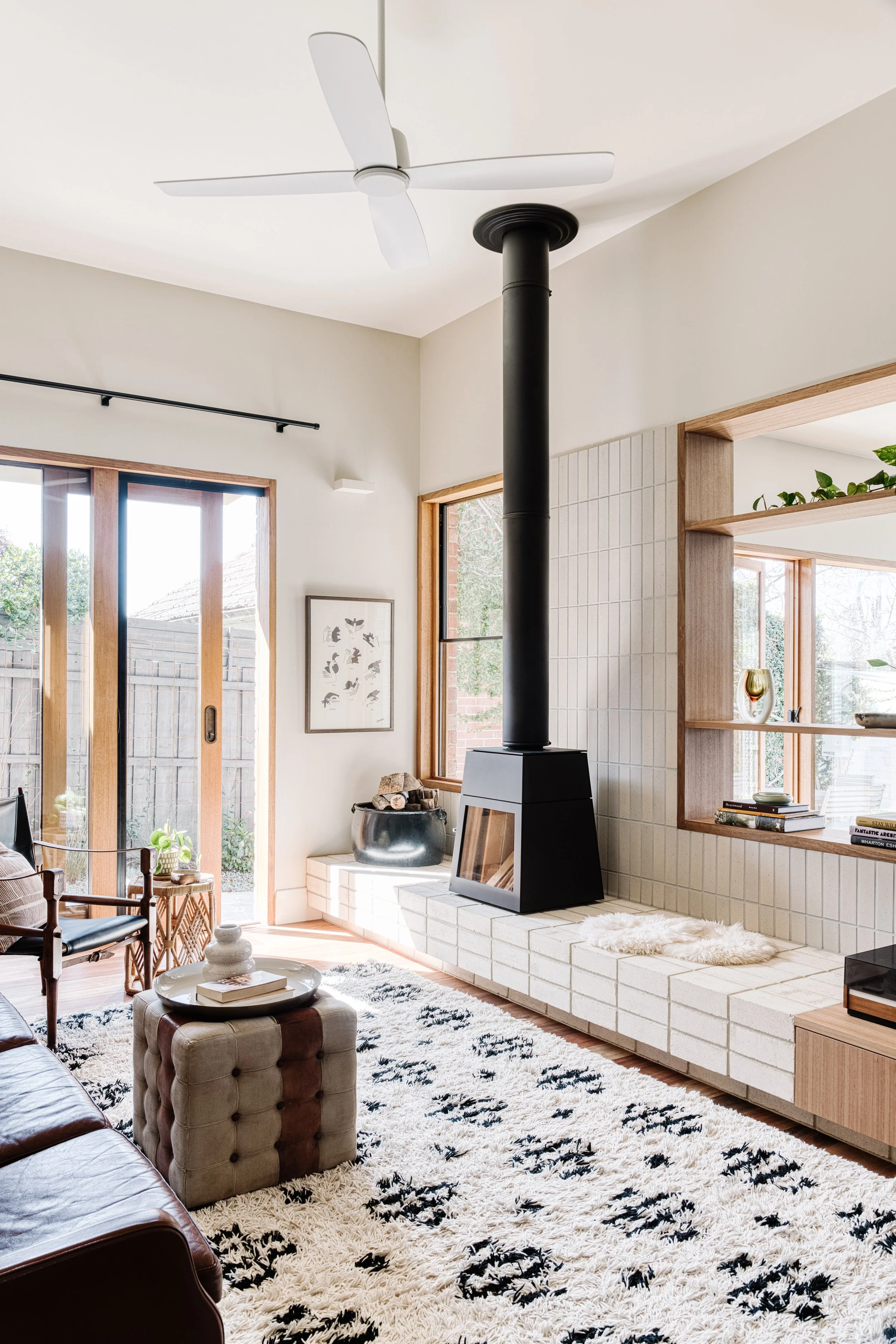 Living room with a modern fireplace, wooden framed windows, a patterned rug, and a mix of contemporary and vintage decor.