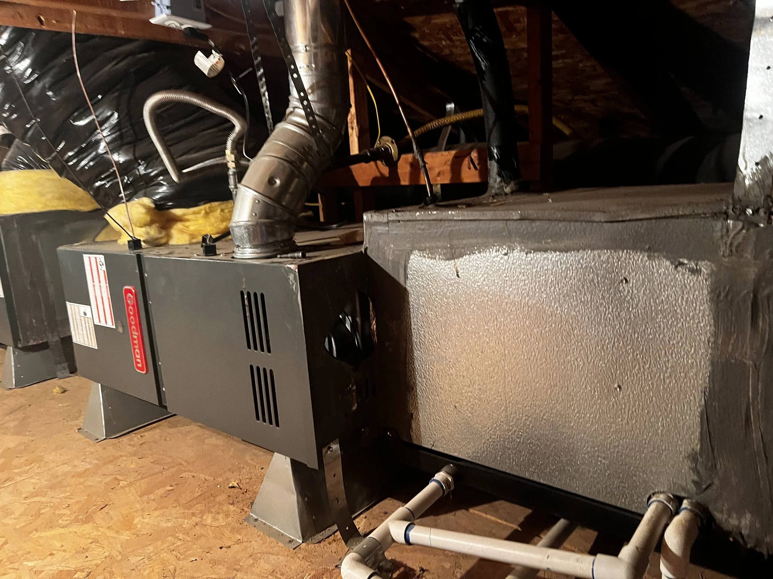 HVAC furnace system installed in an unfinished basement with visible pipes, ducts, and insulation.