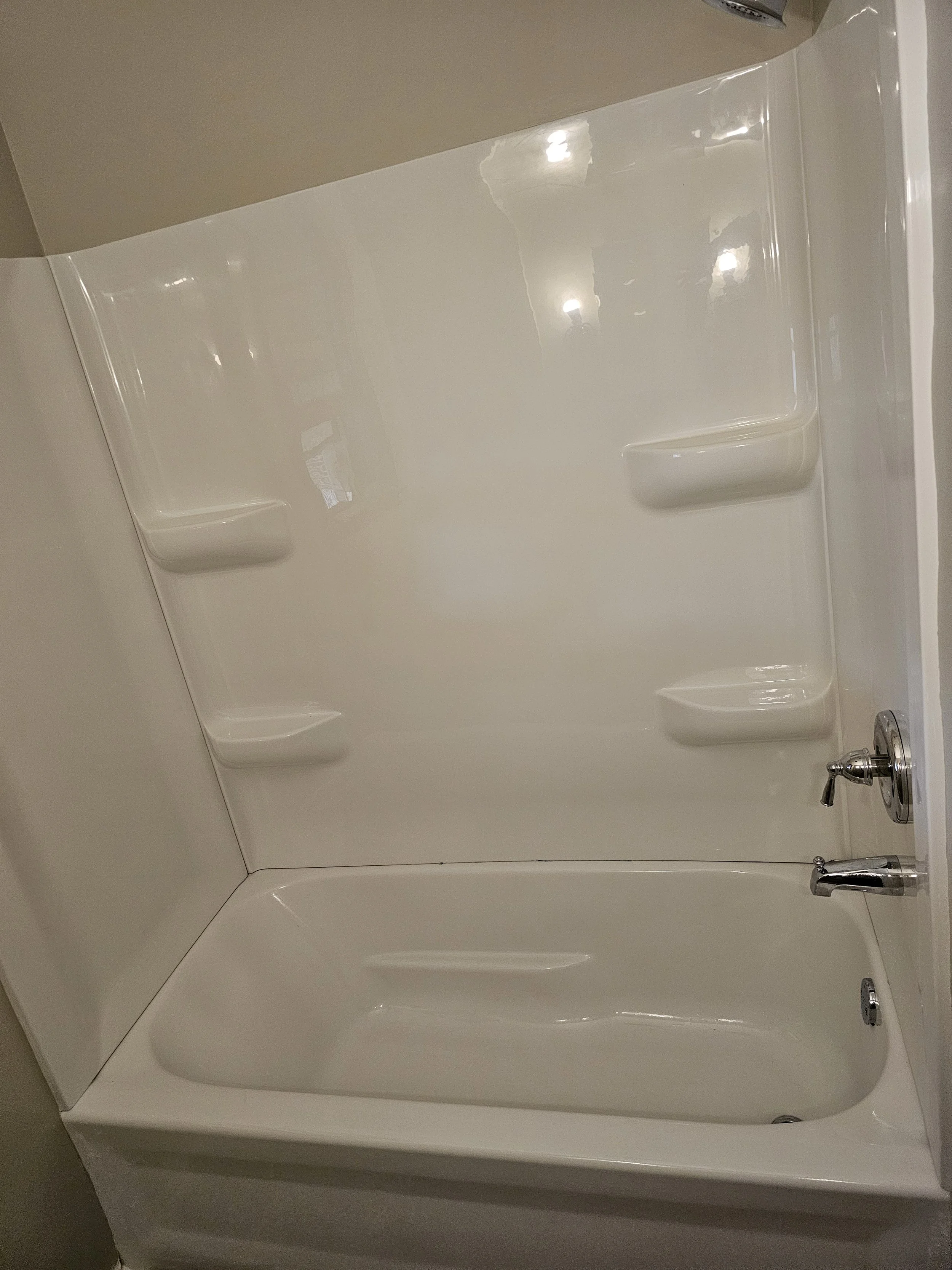 White bathtub with built-in shelves on the wall in a bathroom.