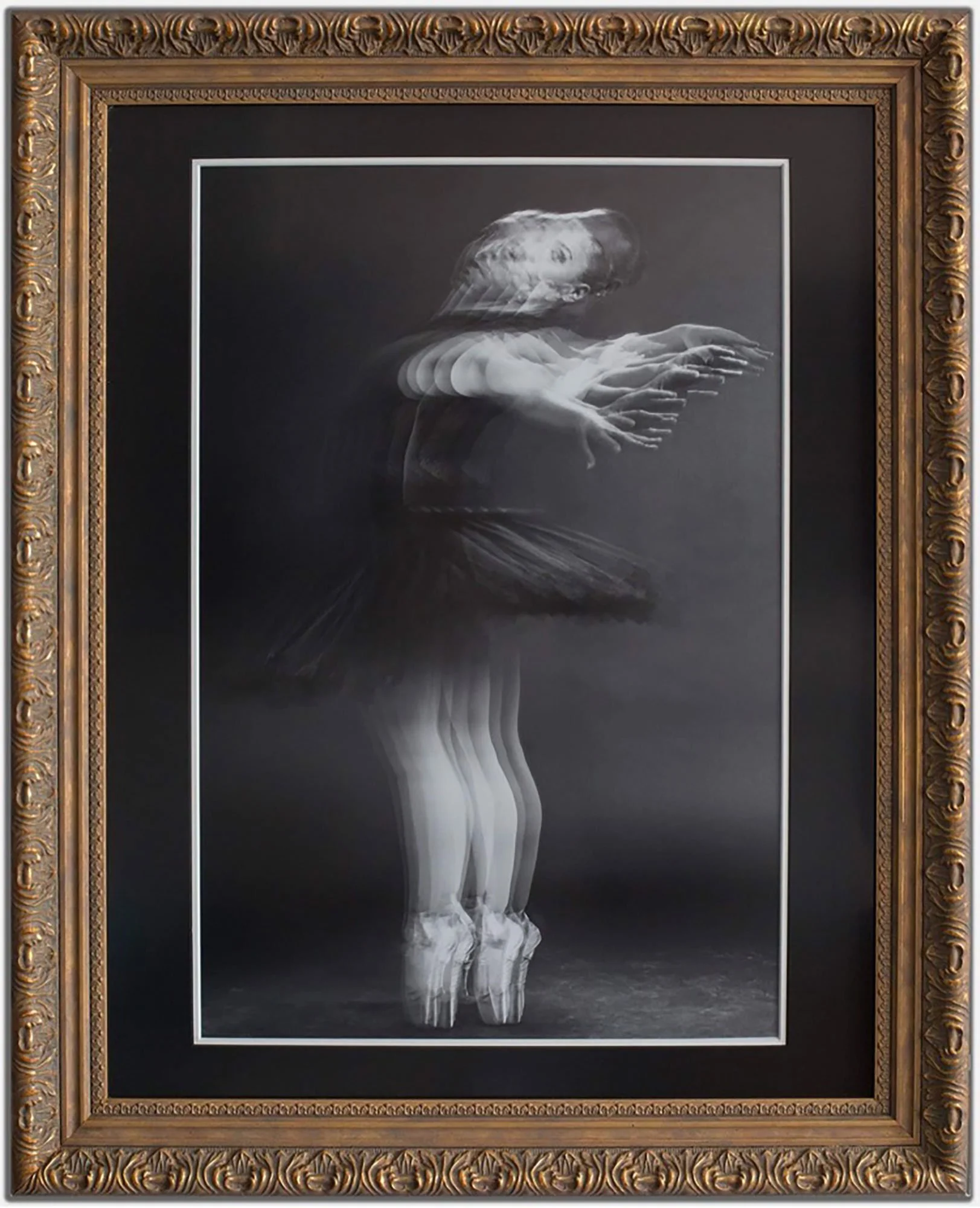 A framed black and white photograph of a ballerina in motion, creating a ghostly, overlapping effect with multiple ghost images of her arms, legs, and face, emphasizing movement and grace.