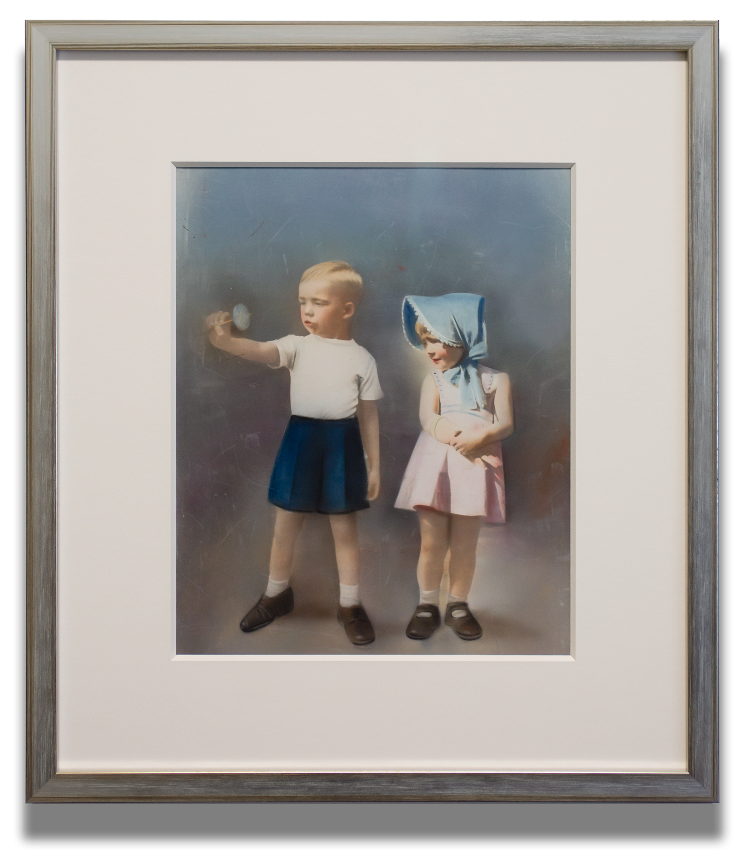 A vintage hand coloured portrait photograph custom framed using museum quality conservation materials and a refined silver wood moulding. The soft pastel tones, oversized acid free matting, and carefully balanced presentation allow the delicate chara