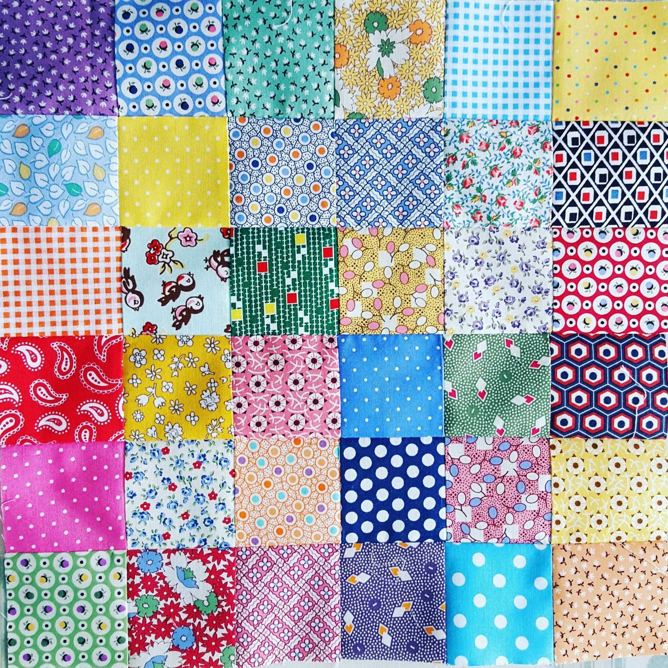 A colorful quilt made of small fabric squares with various patterns and colors.