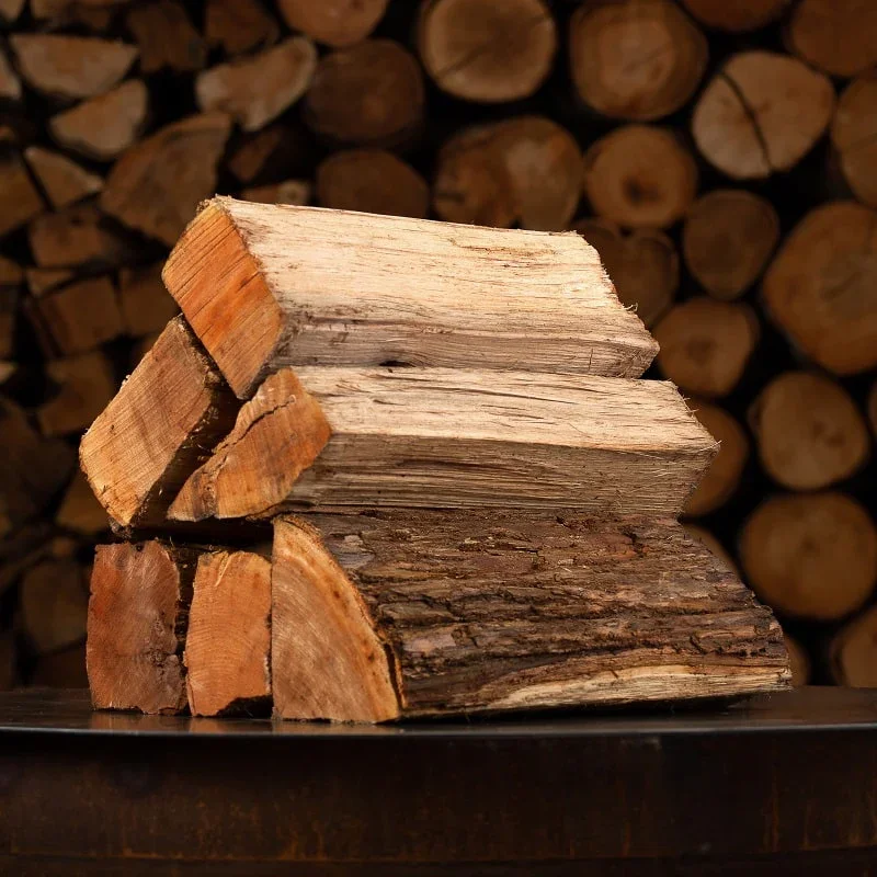 Stacked firewood logs against a background of cut wood logs