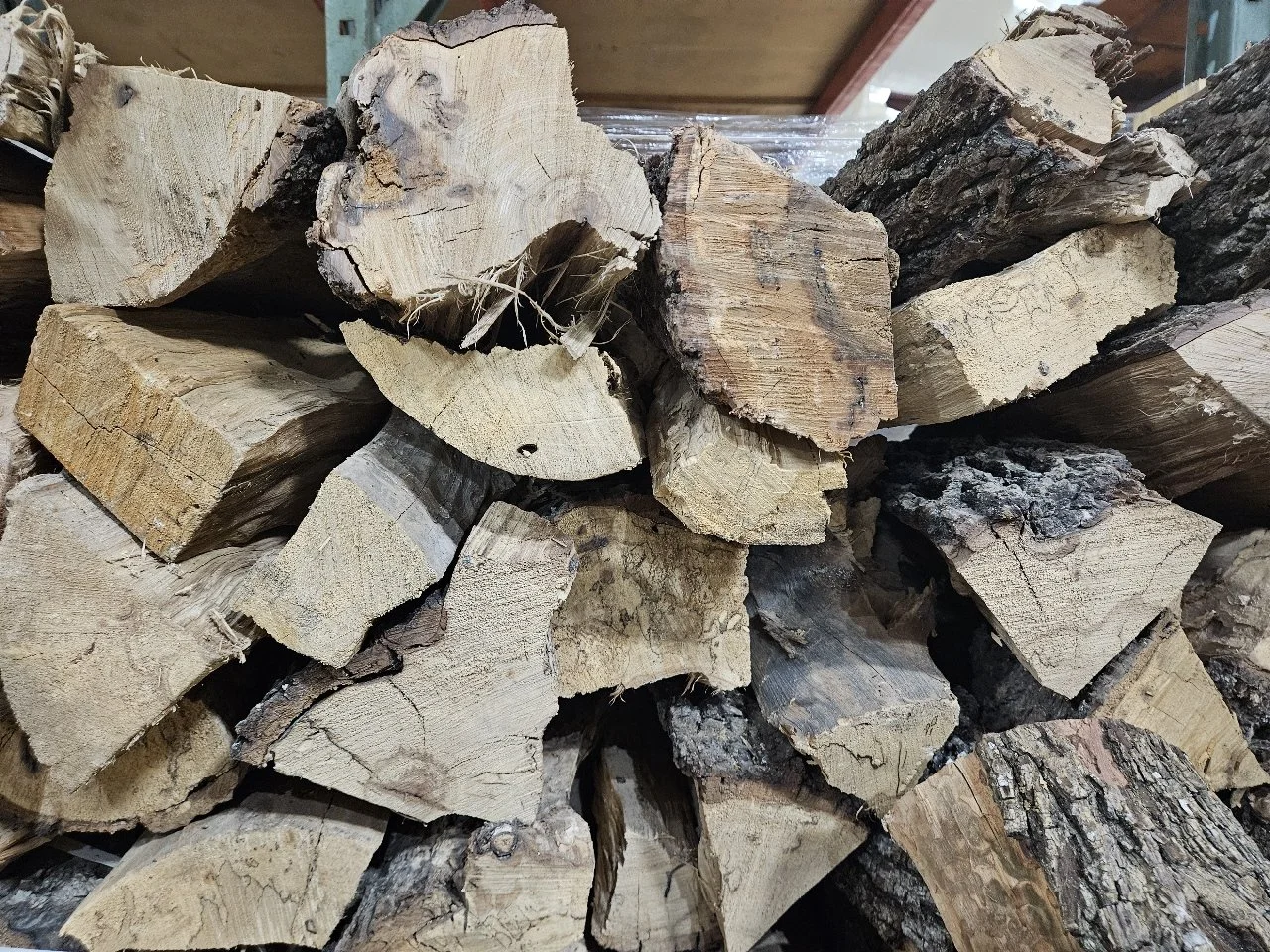 Stacked firewood logs with rough textures and bark, in an indoor setting.