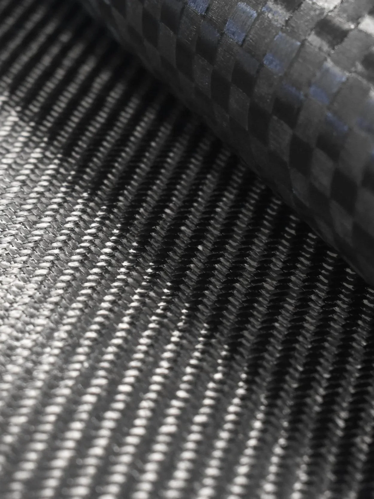 Close-up of a rolled-up black carbon fiber material with a textured, woven pattern.