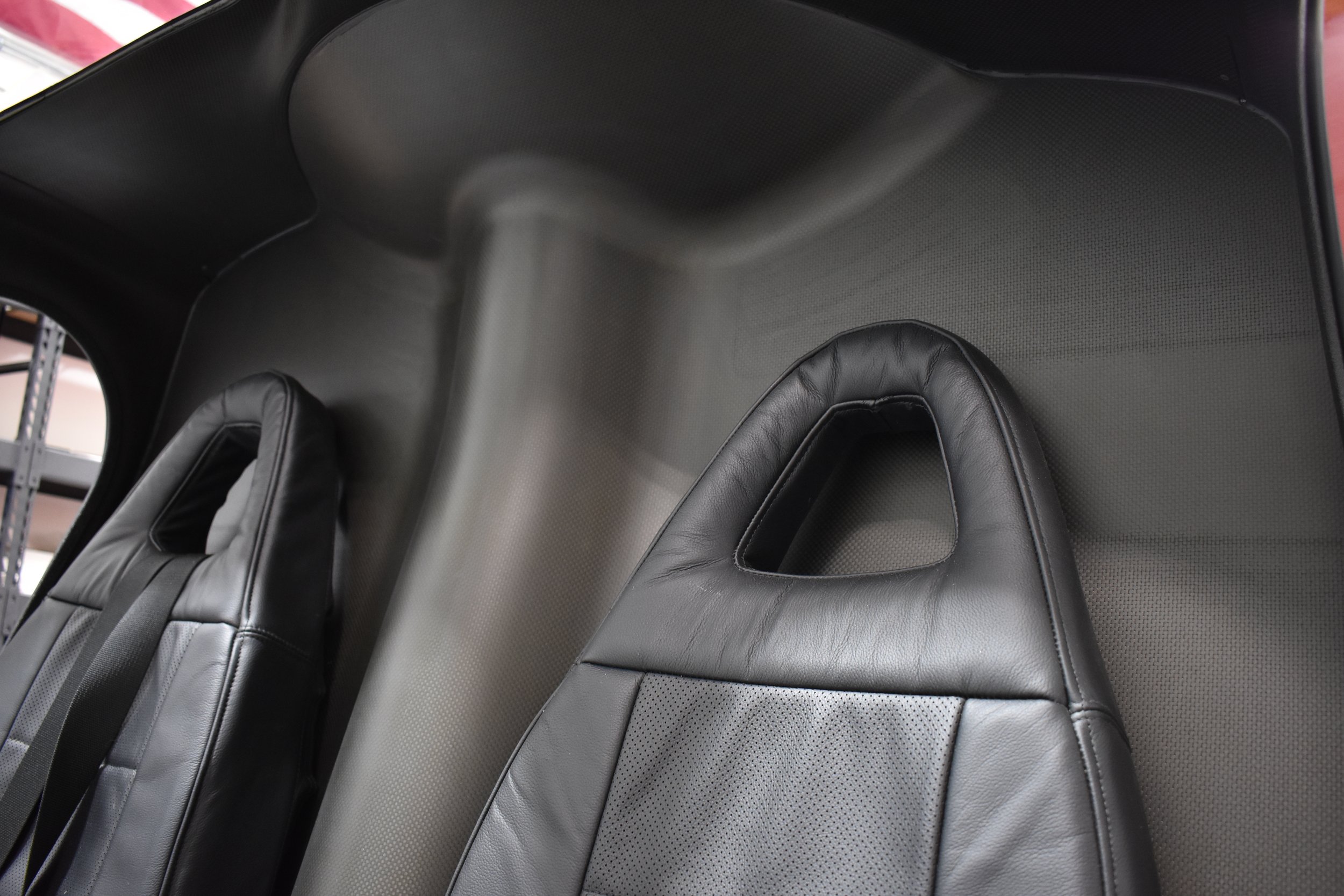 The interior of a vehicle showing black leather seats with a headrest and side panels.