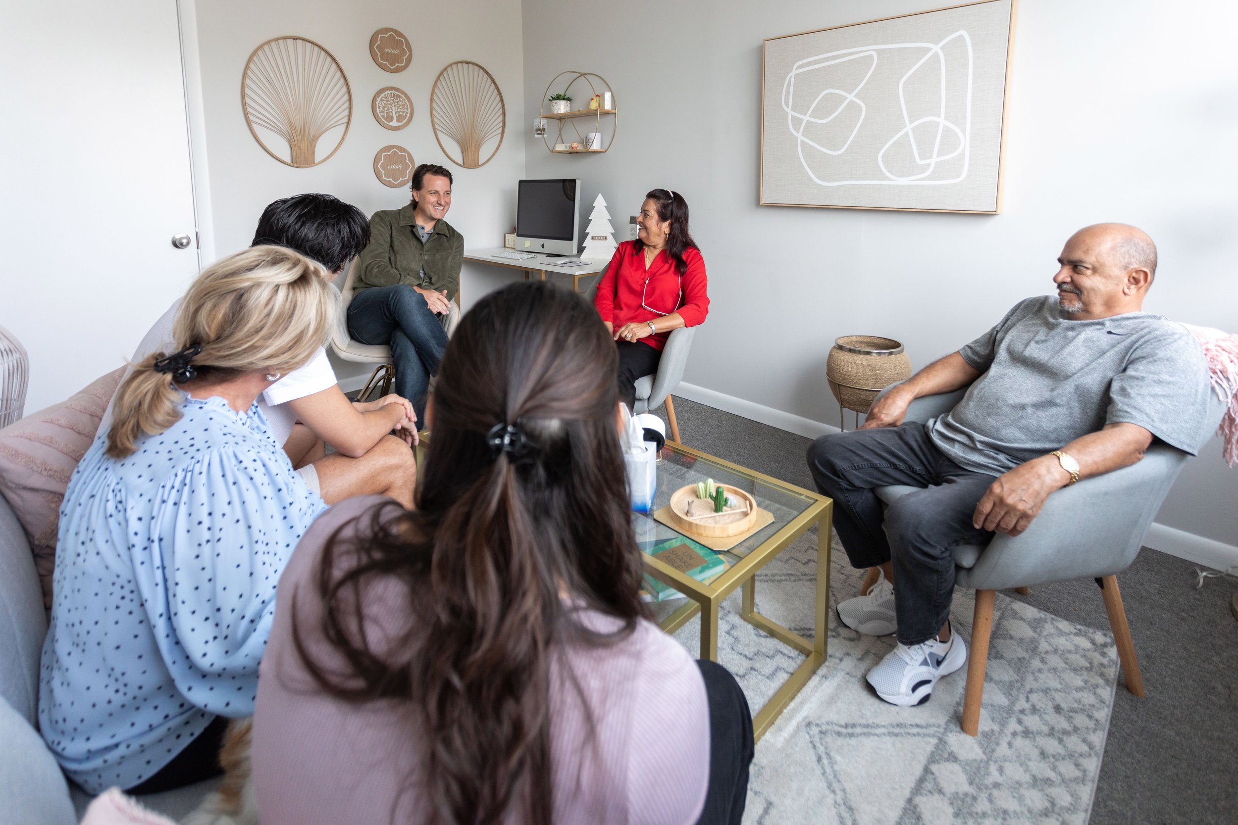 A group therapy session at the Florida Relationship Institute with seven diverse adults seated, engaging in conversation.