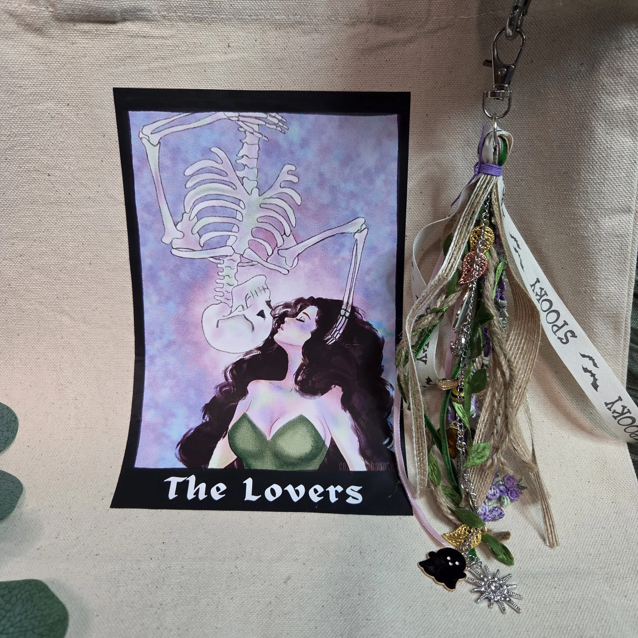 canvas tote bag with a tarot-style drawing of a woman kissing an upside-down skeleton descending toward her with a unique charm.