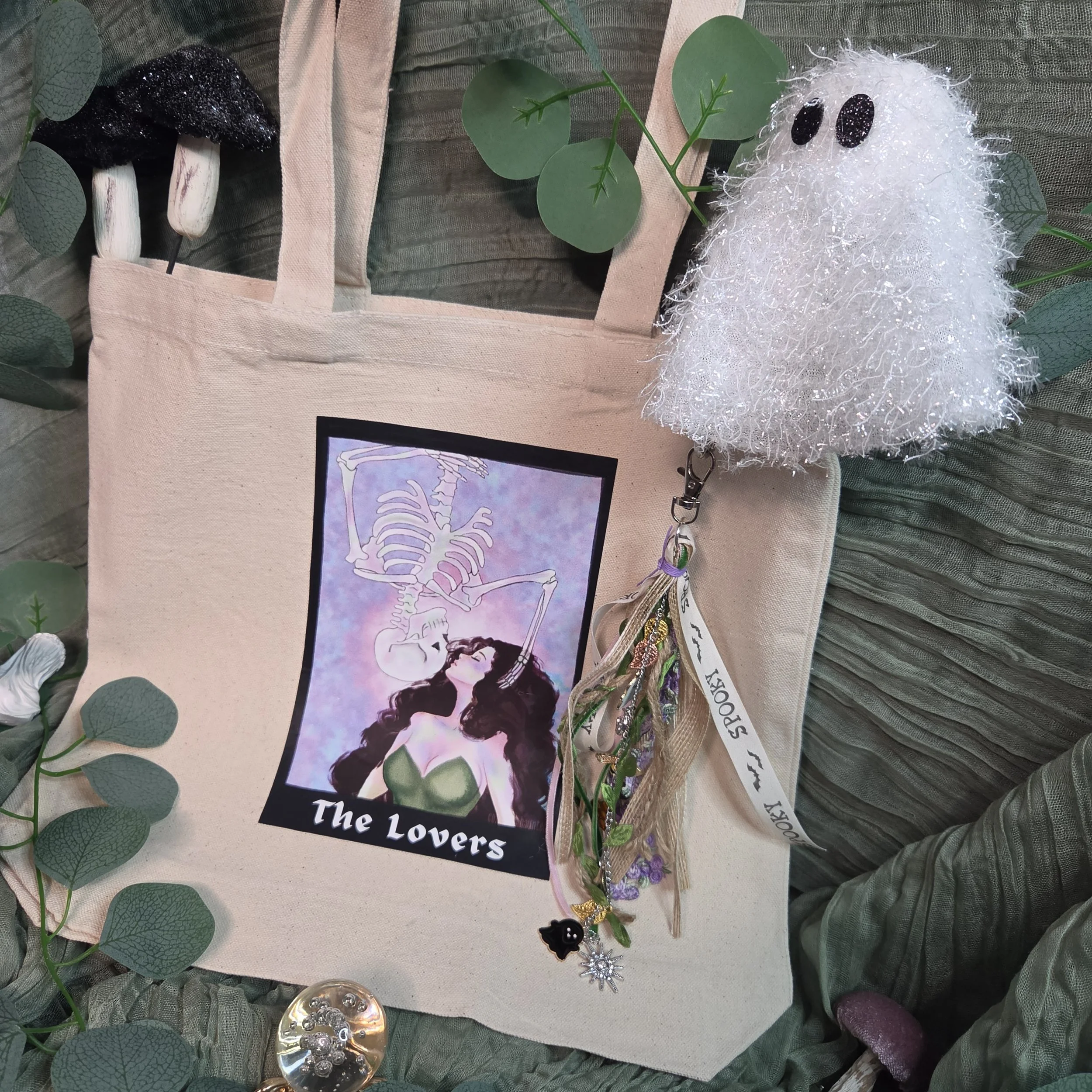 canvas tote bag with a tarot-style drawing of a woman kissing an upside-down skeleton descending toward her with a unique charm.