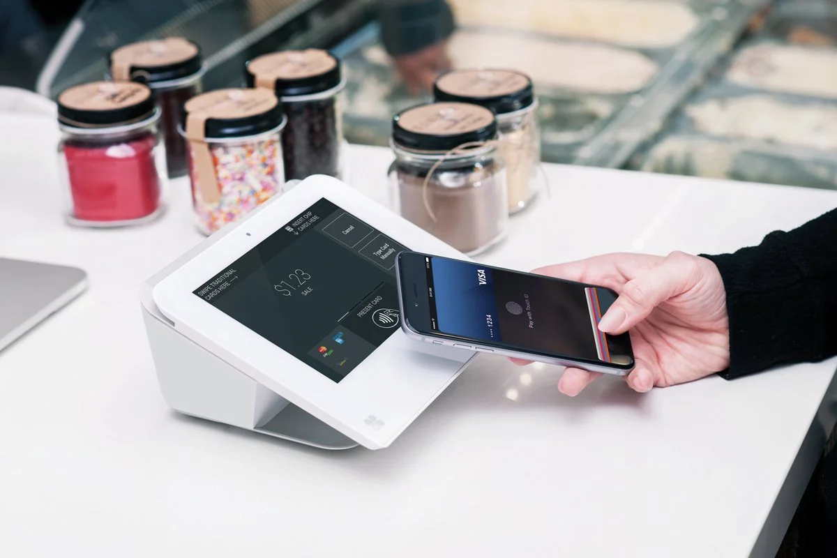 Customer making a contactless smartphone payment at a checkout terminal.