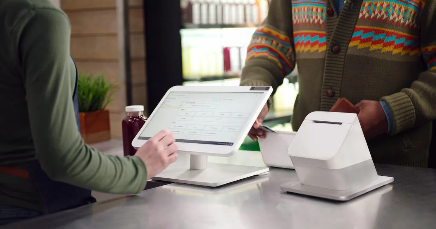 Customer completing a digital payment on a touchscreen checkout device in a store environment.