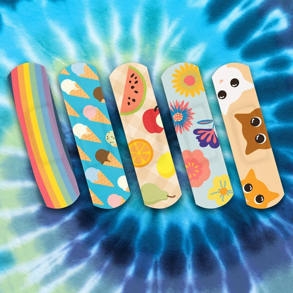 Six colorful hairbands with various patterns and designs, lying on a tie-dye fabric background.