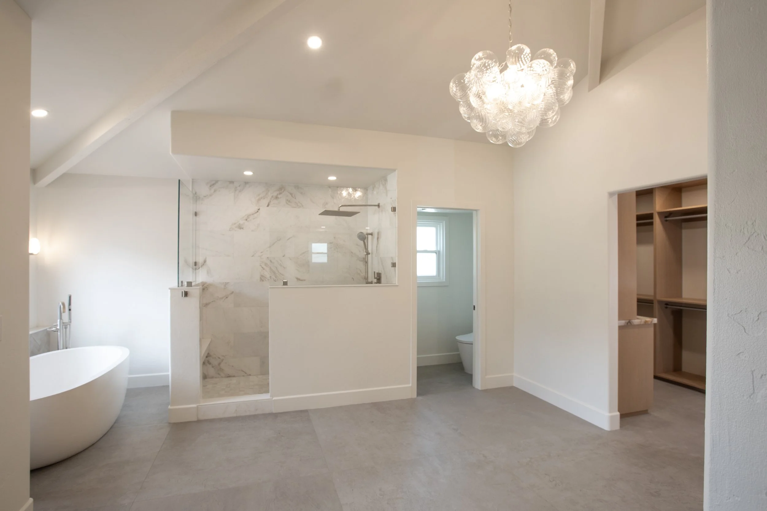 marble tiled shower white modern concrete bathtub, oversized gray textured tile floor 