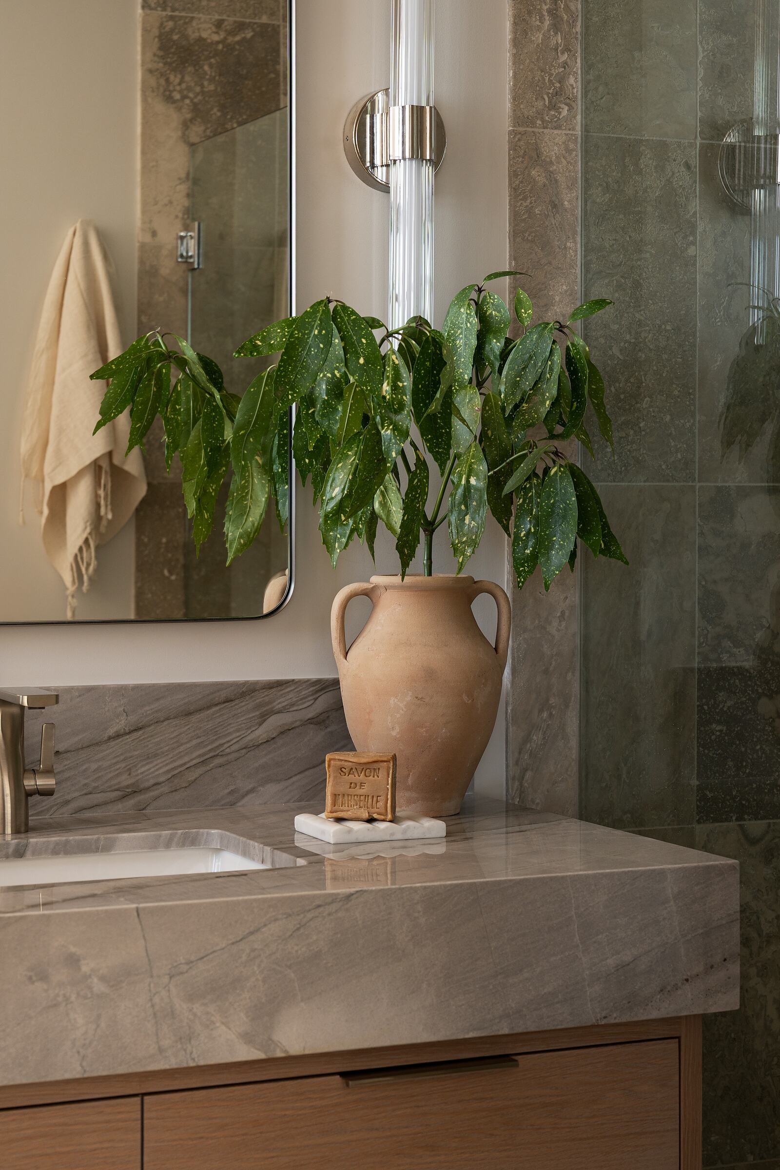 Terracotta urn on Silver Moon quartzite against a green stone shower surround