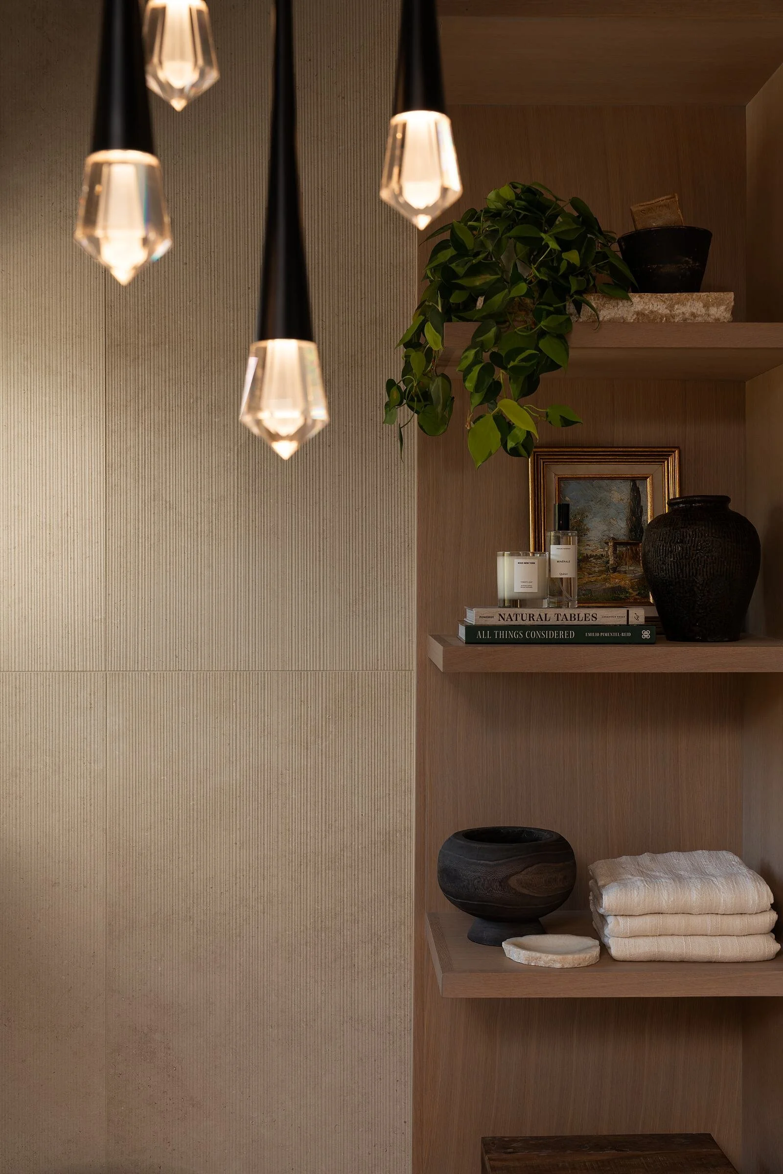 Pendant lights above styled open shelving in a spa bath