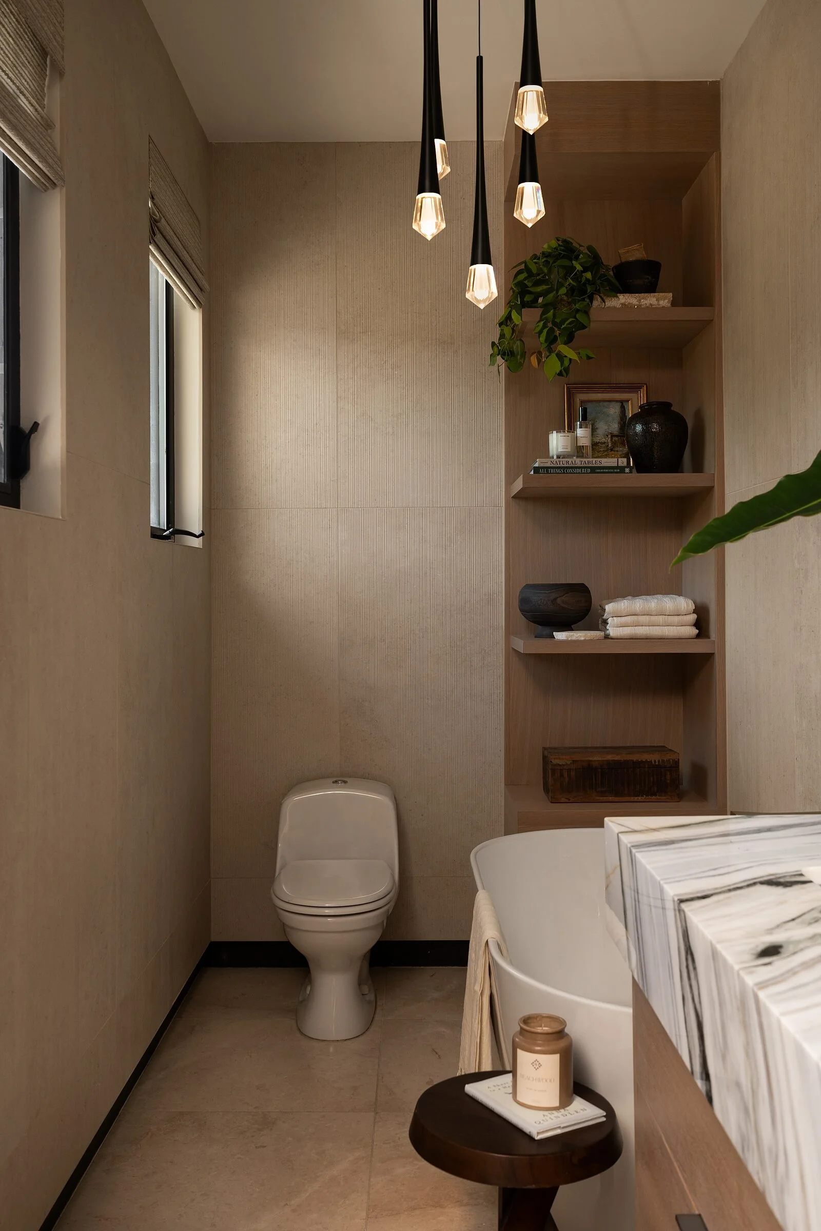 White oak shelving and pendant lighting beside a freestanding tub