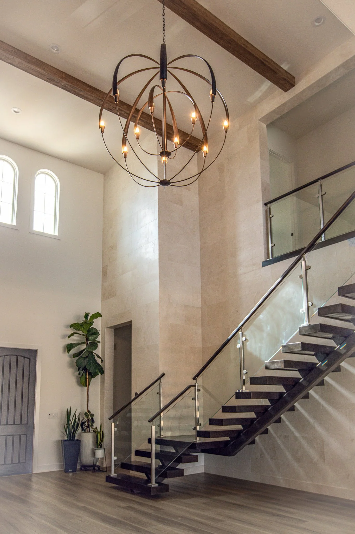 two story entry floating staircase travertine lined walls oversized globe iron chandelier 