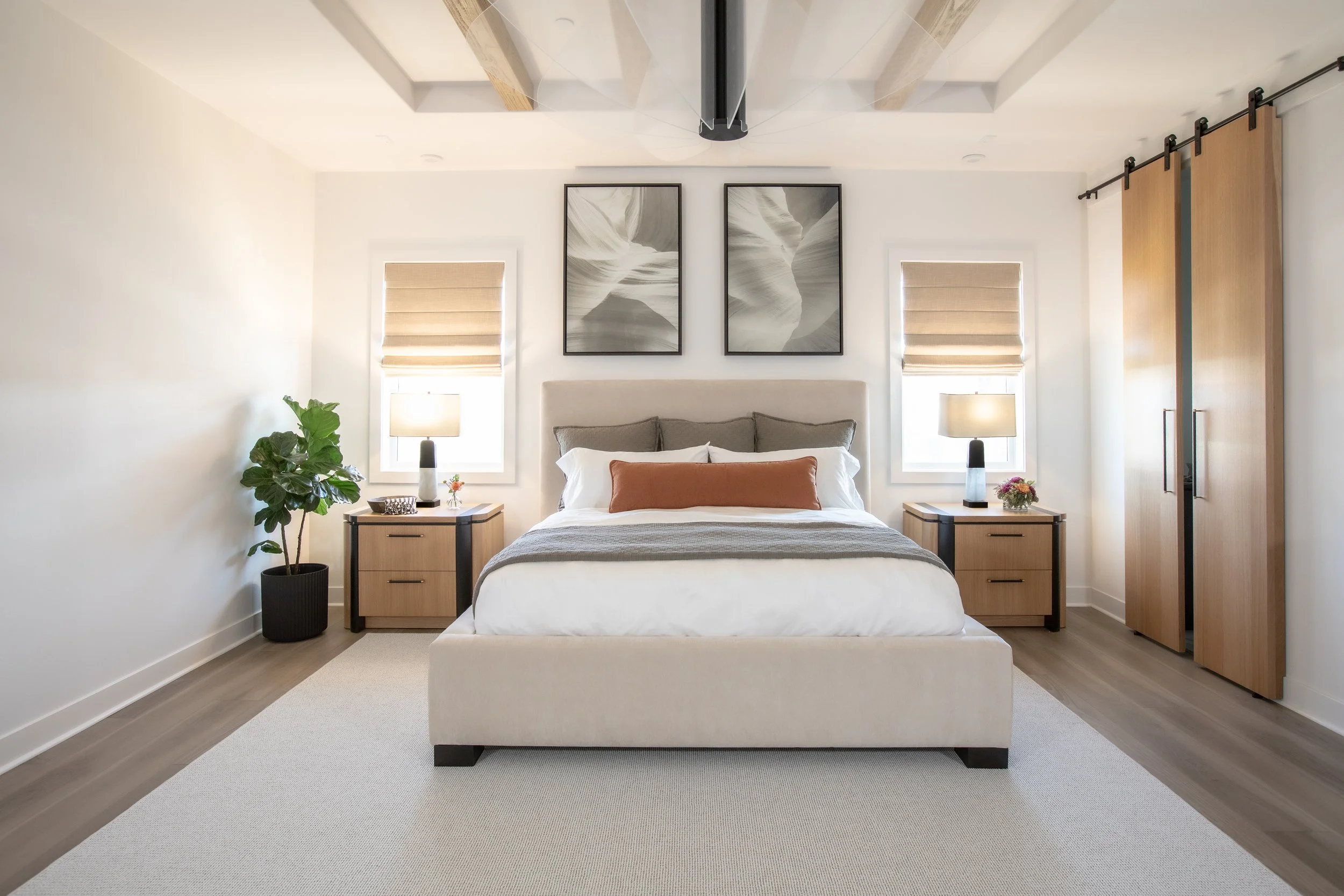Primary bedroom with custom upholstered sage and white bedding and rust lumbar pillow and alabaster lamps with white oak custom nightstands
