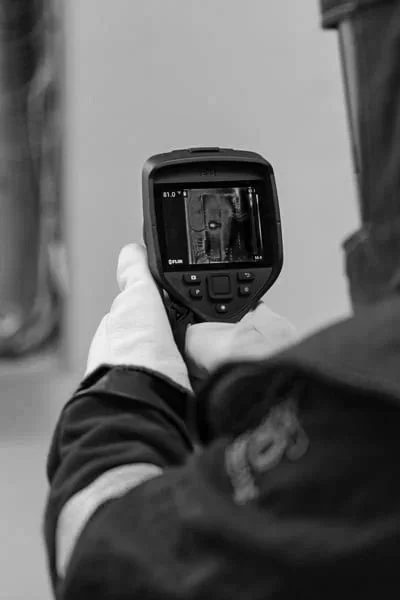 A person in uniform holding a camera or thermal imaging device, capturing an image of an animal or object.