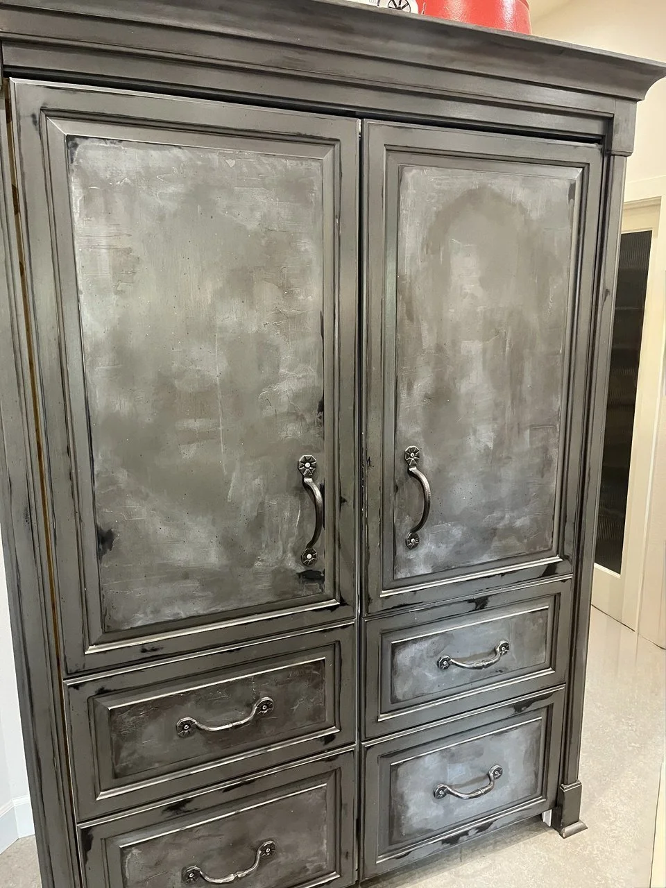 A large gray metal cabinet with two doors and four drawers, showing a distressed finish and silver handles.