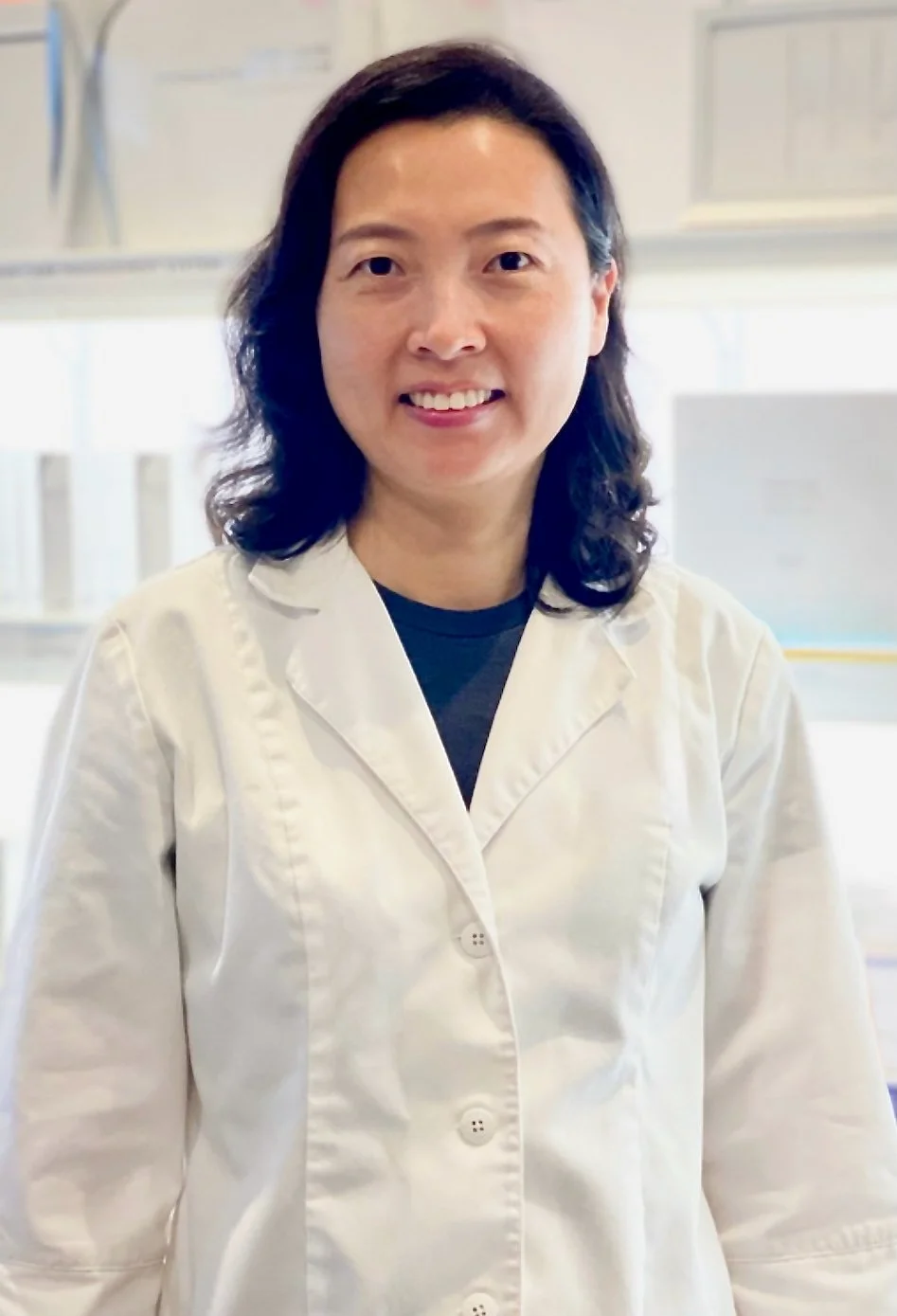The founder of MoonSun Esthetics wearing a white lab coat standing in a laboratory.
